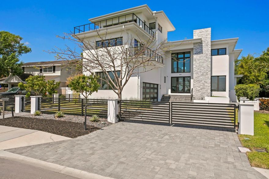Experience elevated modern living in this 2019-built residence by TB Homes, ideally located on Davis Islands—one of Tampa’s premier waterfront neighborhoods. This home was constructed to newer building codes and features elevated living, block construction, and impact-rated windows and doors. The main level welcomes you with a grand open-air foyer, floor-to-ceiling glass, and a cable-railed staircase. The expansive great room showcases a dual-sided 60-inch electric fireplace and retractable sliders. Entertain with ease in the bonus room featuring a roll-up pass-through from the wet bar to outdoor bar seating, complemented by a sleek designer kitchen with quartz waterfall island, marble backsplash, Sub-Zero and Wolf appliances, and butler’s pantry. A private guest suite completes the first floor. A four-stop elevator provides access to all levels, including a rooftop deck. The second floor hosts an elegant primary suite with morning bar, spa-style bath with soaking tub and dual vanities, and a 200+ sq ft custom walk-in closet. Three additional bedrooms, media room, and large laundry complete this level. The rooftop terrace features open-air and covered lounge areas, outdoor kitchen, half bath, and panoramic views of the Seaplane Basin and Davis Islands Yacht Club. The outdoor area offers a heated saltwater pool and spa, travertine deck, cypress-ceiling lanai with summer kitchen, and pool bath. Additional features include new pool equipment, turf, EV charging station, Control4 smart system, hardwood flooring, level 5 drywall, and designer finishes. Davis Islands residents enjoy nearby amenities with convenient access to top schools, shopping, dining, and sports venues.