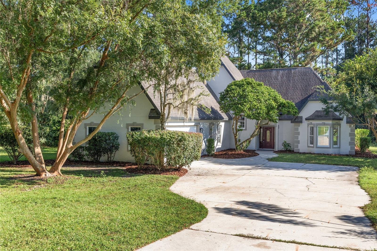 Tucked away beneath a canopy of mature trees, this grand two-story home feels like a private sanctuary at the end of a long, quiet drive. With five bedrooms, three and a half baths, and over 3,000 square feet of charm, it’s a place where elegance and warmth live in harmony.
Inside, sunlight pours across rich engineered hardwood floors, crown molding frames each room, and thoughtful details make the home feel both refined and inviting. The formal dining room was made for gatherings, the cozy fireplace anchors the living space, and the downstairs study offers a quiet corner for focus or reflection.
The expanded primary suite is its own retreat, complete with a sunroom for morning coffee and a spacious bath for unwinding at day’s end. Upstairs, a bonus room carries the air of a library or sitting room, perfect for curling up with a good book.
Freshly painted, with new flooring in the kitchen and study, a new screen enclosure on the lanai, and all-new windows already on the way, the home oozes with timeless character. And beyond the walls, the land itself is something special—zoned for horses, draped in privacy, and set far from the road, it offers space to breathe and grow. This isn’t just a house. It’s a home with presence, charm, and soul—ready for its next chapter.