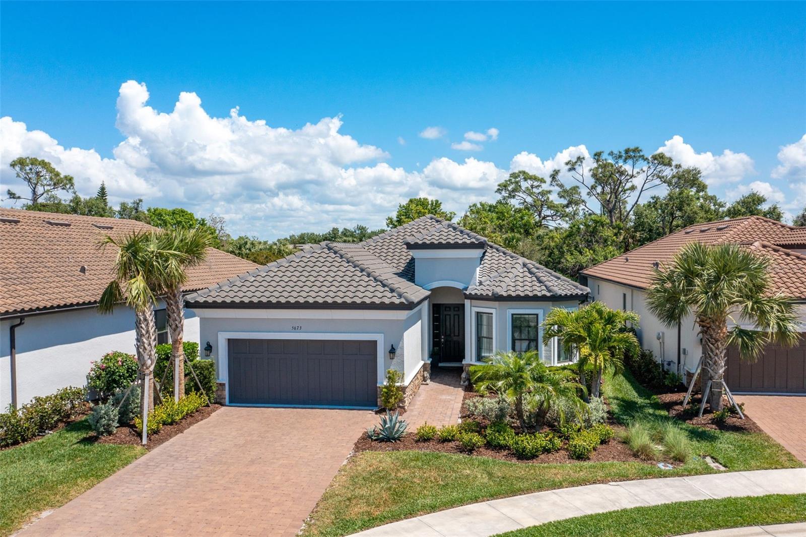 Welcome to Bellacina by Casey Key, an exclusive gated community in Nokomis, offering the best of coastal elegance and convenience. This meticulously designed 3-bedroom, 3-bathroom pool home features a den and a spacious tandem 3-car garage. Lush landscaping creates a captivating first impression, leading into an interior where luxury abounds with soaring 10-foot ceilings, 8-foot doors, and soft-close cabinetry throughout. The gourmet kitchen is a chef’s dream, boasting 42-inch cabinetry, top-of-the-line stainless steel appliances including a gas range, a prep sink in the island, and a walk-in pantry, making it perfect for both everyday living and entertaining. The open-concept design ensures seamless flow between living spaces, enhanced by two sliding glass doors that open from the family room and kitchen to the expanded screen-enclosed lanai. Designed for year-round enjoyment, the lanai offers a large covered area, perfect for dining, lounging, or entertaining, rain or shine. The heated pool and spa provide a private retreat, surrounded by lush landscaping that enhances both privacy and ambiance. Whether you’re enjoying a morning coffee in the shade, hosting a sunset gathering, or unwinding in the spa after a long day, this outdoor oasis is a highlight of the home. The primary suite serves as a true retreat, featuring an en-suite bath with a spacious tiled shower, dual sinks, and a private water closet for added privacy. One guest bedroom includes its own en-suite bathroom, creating a private guest suite ideal for family or visitors, while the other offers a pocket door to transform it into a second suite. The versatile den, adorned with French glass doors, is perfect for a home office or library, offering flexibility to suit your lifestyle. Bellacina by Casey Key is a maintenance-free, resort-style community offering luxury amenities and an active lifestyle. Residents enjoy a clubhouse, heated lagoon pool and spa, fitness center, fire pit, tennis and bocce courts, dog park, and scenic walking trails. An on-site activities director keeps the social calendar full of events. Located just minutes from Casey Key and Nokomis Beach, this gated community provides easy access to pristine Gulf waters, world-class golf courses, the Legacy Trail for biking and walking, and nearby waterfront dining and entertainment. Experience the best of coastal Florida living in this sought-after neighborhood!