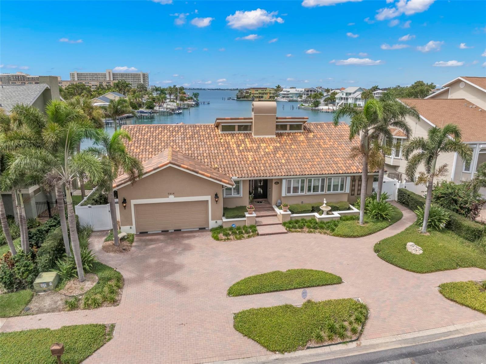 Discover the lifestyle you've been looking for in this well elevated single-story waterfront home, located within the gated waterfront enclave Pasadena Yacht & Country Club. This "high and dry" residence has been flawlessly updated to offer a harmonious blend of elegance and modern amenities. Upon entering, you'll quickly be captivated by the exquisite gourmet kitchen, a chef's dream featuring a spacious island, state-of-the-art Subzero appliances, a European enamel natural gas stove, and premium solid wood cabinetry. Adjacent to the kitchen, wine aficionados will appreciate the custom-designed wine bar area, showcasing storage for hundreds of bottles—perfect for curating your private collection. The home's split bedroom layout ensures privacy, with the expansive primary suite offering a peaceful retreat. The remodeled en-suite bathroom is your personal spa, featuring dual vanities, a separate shower, and a charming claw foot tub. Outdoors, immerse yourself in resort-style living. The covered outdoor kitchen and seating area are ideal for entertaining, providing stunning views of Boca Ciega Bay while being safeguarded by electronic hurricane shutters. Relax in the inviting pool with its serene waterfall features, or unwind in the pergola-shaded jacuzzi, perfectly positioned to enjoy the iconic Florida sunsets. Additional features of this exceptional property include hurricane windows and doors, tile roof, a natural gas generator, a dock and boat lift, remodeled bathrooms, and a spacious circular paver driveway. Embark on a lifestyle of unparalleled luxury and convenience in this European-inspired home, where every detail is crafted to perfection. Schedule your private viewing today and step into a world of sophistication and style in the Pasadena Yacht & Country Club.