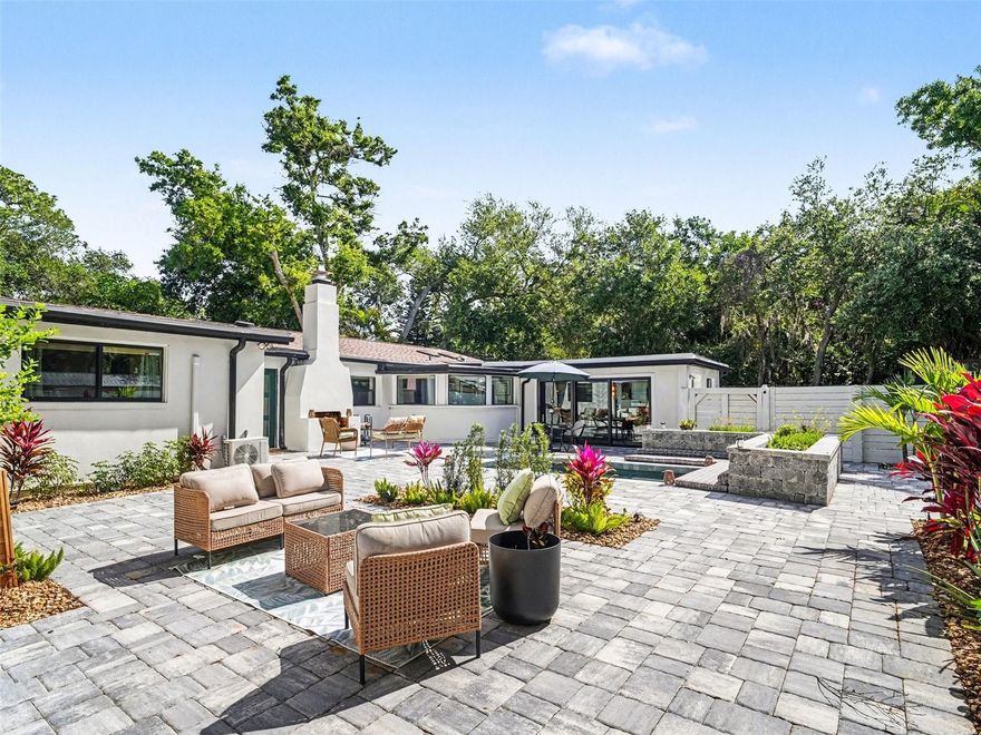 Step into a home that redefines privacy, design, and sophistication.  Priced at $870,000, this fully renovated 3-bedroom, 3-bathroom residence with a dedicated office and pool offers a rare courtyard-style layout where indoor and outdoor living seamlessly intertwine.  Enter through a private gated front courtyard, and you’re immediately welcomed by a heated pool, custom pavers, and a striking outdoor wood-burning fireplace.  Cement planters with cushioned seating surround the pool, creating a relaxed resort-style setting, while a lemon tree and foliage add a natural, tranquil touch to the courtyard oasis.  This is an intimate, resort-style setting designed for both private entertaining and everyday living.  The oversized screened lanai extends your living space even further, creating multiple areas to relax and unwind in complete privacy.
Inside, modern upgrades marry timeless design across a beautifully connected living and kitchen layout.  The living room is anchored by a sleek electric fireplace and a mounted picture frame TV against a green tile backsplash, creating a refined focal point that feels both comfortable and elegant.  The kitchen is equally impressive, featuring quartzite countertops, floor-to-ceiling custom cabinetry, and a pot filler above the gas stove.  Seamlessly integrated appliances, including a refrigerator concealed within matching cabinetry, enhance the clean, elevated aesthetic.  A hidden “secret” door within the kitchen leads to a spacious laundry room and full bath, adding practicality while introducing a subtle element of surprise. 
The private office is another standout feature, finished with marble flooring and framed by large windows overlooking the courtyard and pool.  Abundant natural light and serene views create an inspiring workspace, while French doors provide privacy when needed.
New engineered wood flooring flows throughout the home, complemented by updated lighting and new hurricane impact windows and doors for peace of mind.
This home offers the rare advantage of two primary suites, each refined in every detail. The main suite is a true retreat, featuring a private dry bar with a mini fridge, a fully customized 7x17 walk-in closet, and a spa-inspired bath with a soaking tub, expansive walk-in shower, heated towel rack, smart toilet, and designer finishes in warm, sophisticated tones.  The second suite provides its own spacious bath and beautifully finished walk-in shower, ideal for guests or multigenerational living.  The third bedroom has beautiful views of the pool through the sliding glass doors.
Additional upgrades include a whole-home water filtration system, split A/C units for enhanced cooling, an attic fan, and new fencing surrounding the courtyard.  Parking is abundant with a circular driveway and additional space alongside the fence, comfortably accommodating five or more vehicles.  A separate outdoor shed provides convenient storage for lawn and pool equipment.  Located in a quiet neighborhood just a few streets from the water, this home is a rare find in today’s market, where every detail has been carefully curated for luxury, comfort, and style. Furnishing negotiable!