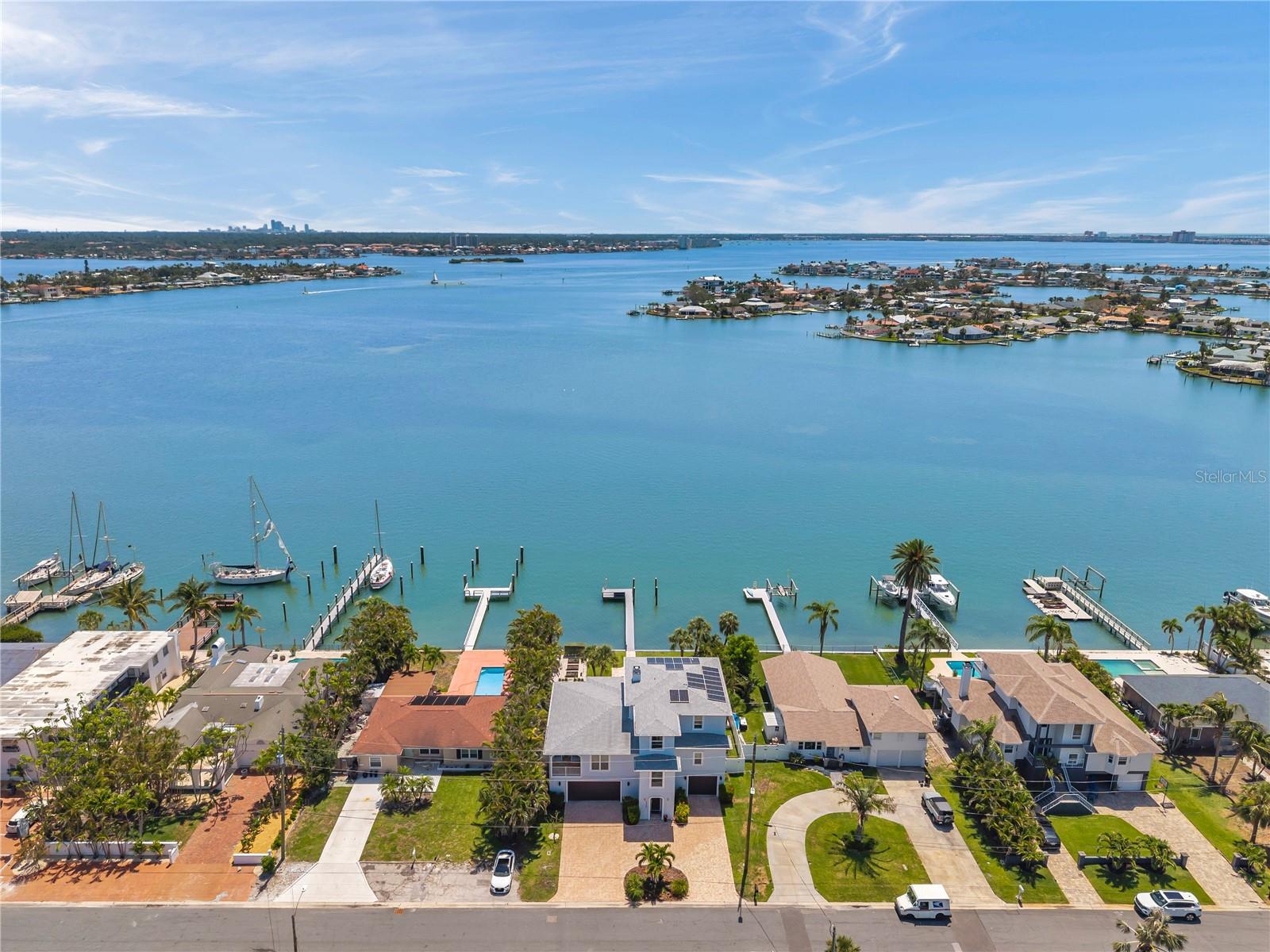 LOCATION! Welcome to this modern waterfront masterpiece located on the wide-open sparkling waters of the INTRACOASTAL and within a short stroll to the BEACH. This elegant, custom-built 3-story residence (2018) captures the essence of refined coastal living, blending high-end craftsmanship, modern energy efficiency, and serene natural beauty. Nestled on an oversized lot with 75 feet of deep-water frontage along Boca Ciega Bay, this home offers the ultimate indoor-outdoor lifestyle. Wake and enjoy sunrise views from your expansive 500+ square foot covered balcony or lanai, unwind at sunset on your private dock, or take a refreshing dip in the stunning saltwater pool surrounded by travertine decking and lush tropical landscaping. Boaters will appreciate the 72-foot deepwater dock—Trex-built and ready for customization—lift-ready with 50-amp service available, plus quick and easy access to the Gulf of Mexico. Step inside to enjoy the ideal open-concept living area on the second floor, extending seamlessly outdoors beyond the expansive sliding glass doors to your covered travertine-tiled balcony living space featuring panoramic bay views. A cozy wood-burning fireplace, wet bar with granite countertops, and elegant crown molding add timeless charm. The gourmet kitchen features solid wood custom cabinets and range hood, a new 5-burner cooktop (2025), double ovens, a huge center island with bar seating, gleaming stone counters, and a reverse osmosis water filtration system. The walk-in pantry and laundry room offer exceptional storage with custom cabinetry, pull-out shelving, a deep cast iron laundry sink, and even space for a full-size wine fridge. Retreat to the showstopping primary master bedroom suite on the second floor - your own personal sanctuary of luxury and tranquility with expansive water views from both the bedroom and bathroom. There's a chandelier-lit jetted tub perfectly positioned by the window and oversized shower with bench seat, a massive awe-inspiring chandeliered walk-in closet, sound-proofed walls and solid-core doors, his and hers marble vanities (hers includes a makeup vanity and hot tools drawer), and spa-worthy marble finishes throughout. The third floor boasts three more bedrooms offering equal elegance and luxury finishes. Additional highlights include an ELEVATOR, SOLAR PANELS (paid off), built-in audio system (in home, backyard and balcony), hardwood flooring, an oversized 4-car garage (2 of the 3 garage doors are oversized for large vehicles), three EV CHARGERS, a Generac generator switch, premium water softener, and a new water heater (2025). The home's insulated steel construction ensures superior strength and energy efficiency. Perfectly located in one of St. Pete Beach’s most desirable waterfront neighborhoods with NO HOA, this home is within easy walking distance from local dining, shopping, and the beloved Corey Avenue Sunday Market. Trendy and vibrant downtown St. Petersburg and major airports are also conveniently close by. And while the beach is only a short walk away, you may never want to leave the paradise of your own backyard! This is a rare opportunity to own a truly one-of-a-kind luxury coastal home where every detail has been carefully considered for both beauty and function. Schedule your private tour today.