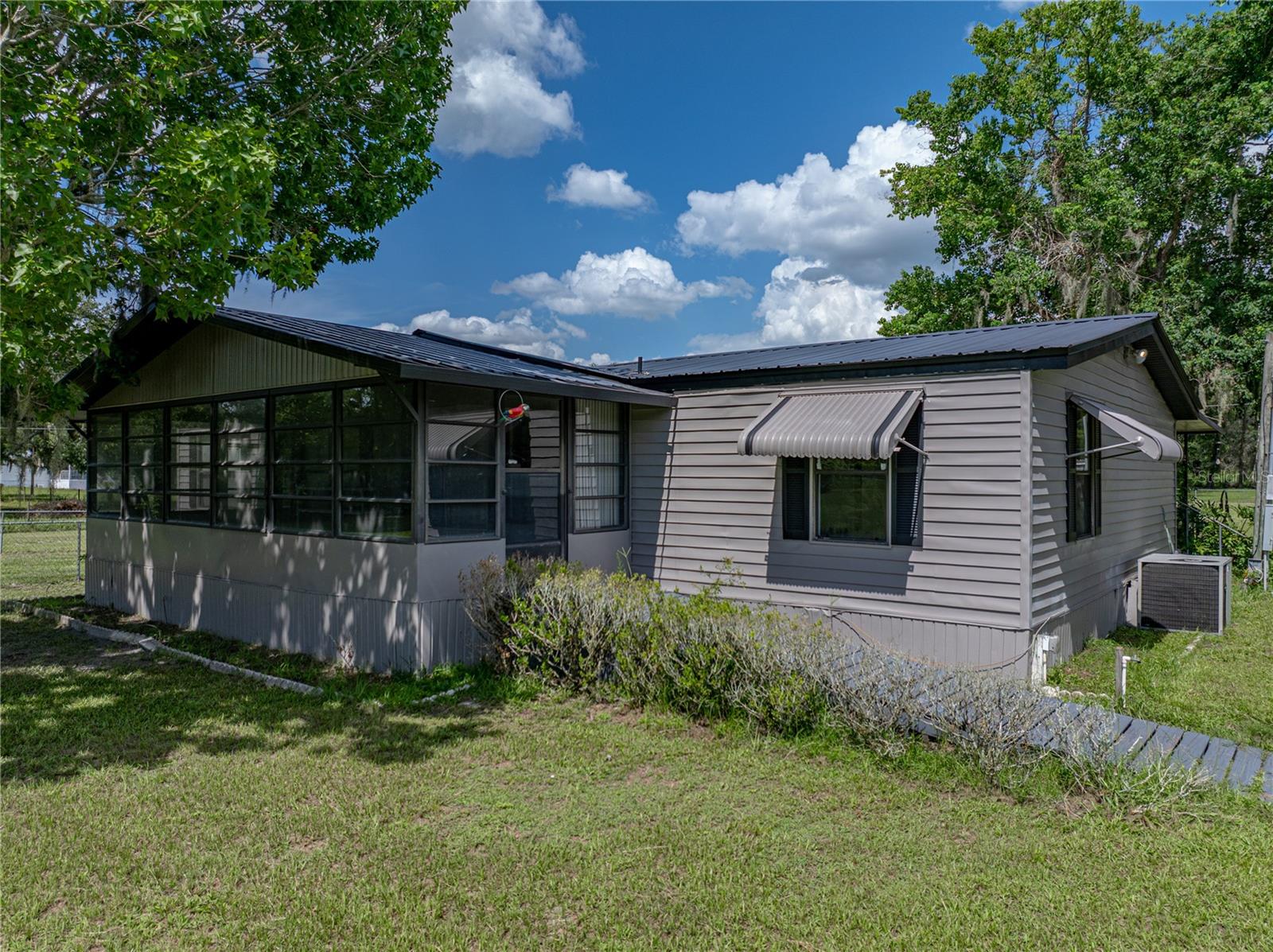 EXPERIENCE A QUIET COUNTRY LIFESTYLE at this well-maintained home on 2.5 acres. The spacious 3 BD/ 2½ BA home offers plenty of outdoor space to enjoy peaceful solitude and nature. An inviting enclosed porch leads into the living room anchoring the open concept to the family room, dining room and kitchen. The spacious family room/dining combo offers a fireplace flanked with built-in shelving and the access to the huge screen porch expands the space for relaxation and when entertaining. The attractive kitchen offers plenty of storage and workspace with beautiful wood cabinets, contrasting backsplash, a convenient pass-thru opening, and the adjacent laundry room. The split bedroom plan gives privacy to the master en suite that boasts a walk-in closet with built-ins and bathroom with large tiled shower. The opposite side of the home is the second bathroom with tub and vanity, this bathroom is convenient to the living area and the additional bedrooms. Some Great Features include: NEW interior/exterior paint, Electrical, Plumbing & HVAC Motor, 1 yr old appliances, 3 Sheds w/elec., 2 carports and a greenhouse! The entire 2.5 Acre property is fenced and an interior fenced lawn keeps family and pets close by. This property allows for many options, as it stands in an unincorporated area without deed restriction and NO HOA. Enjoy this peaceful, quiet location situated near beautiful parks with natural springs for canoeing/kayaking/boating, hiking, and nearby cycling trails and horseback riding. Located a short distance to town for all necessities and close to I 75, the Florida Turnpike leading to an abundance of options for dining, entertainment and shopping. Call to schedule a viewing of this great property, call today this will sell fast!