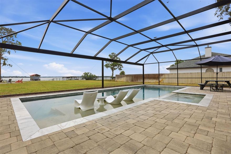 Set along the shore of Lake Dora, this waterfront estate offers a rare blend of privacy, comfort, and relaxed luxury on the Harris Chain of Lakes. Life here moves at a different pace — mornings begin with coffee by the water, afternoons are spent boating through scenic lakefront towns, and evenings end with seaplanes and sunsets reflected across the lake. Just a short drive or boat ride from the charm of Mount Dora and historic Eustis, the location offers the perfect balance of peaceful retreat and vibrant small-town lifestyle. The outdoor living spaces were designed to be enjoyed year-round. A resort-style pool with a lap lane and spa creates the feeling of a private getaway, while the fire pit area with its cowboy cauldron invites long evenings under the stars with friends and family. Along the shoreline, the newer composite dock, covered boathouse, and boat lift make it easy to explore the chain of lakes whenever the mood strikes. The fully fenced backyard adds to the sense of seclusion and serenity, while impact-rated windows and doors and a whole-home Generac generator provide an added layer of comfort and confidence during every season. Inside, the home feels both welcoming and refined. Tall coffered ceilings and rich wood floors add warmth and architectural character, while the remodeled kitchen brings a clean, modern style to the heart of the home. Natural light pours through the living spaces, creating an atmosphere that feels open, calm, and connected to the beauty outside. More than just a waterfront property, this is a home designed for those who value experiences, connection, and the everyday luxury of lakefront living.
