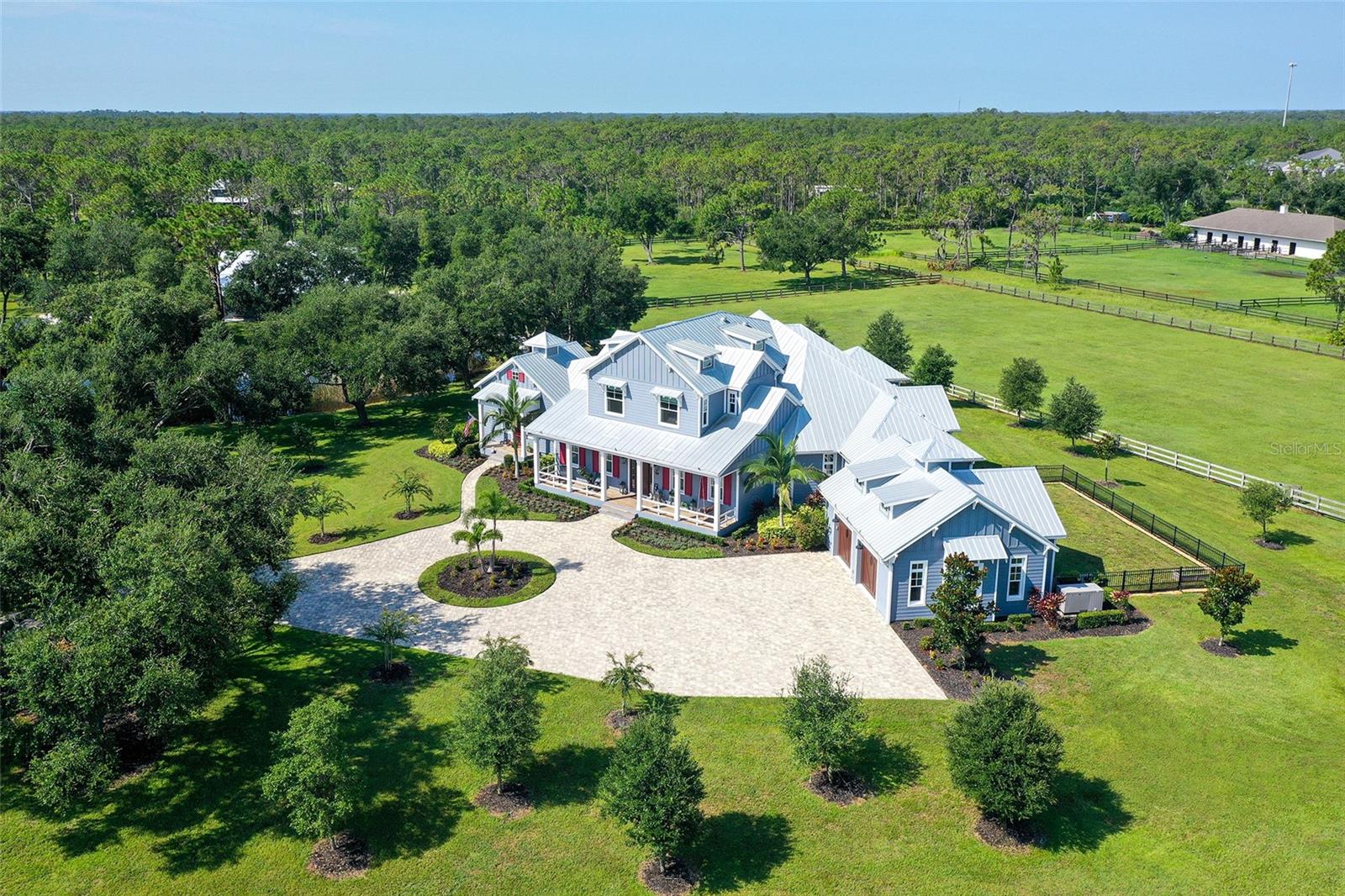 Nestled in Panther Ridge, this gated 9+ acre estate blends luxury and equestrian excellence. A winding paver driveway, lined by majestic oaks, curves past the guest home to the main residence. High and dry with superior drainage, the fenced and cross fenced property features oak, pine, lush pastures and lake views, creating a park-like oasis. Storm-ready with impact-resistant doors, windows, metal roofs, and a whole home generator, peace of mind is ensured. The estate is ideal for multi-generational living and features a 5,003 sq ft u/air smart home built in 2021 (7,185’ total), a remodeled guest home with a 2025 metal roof (2,559 sq ft u/air, 3540’ total), and a state-of-the-art barn, also constructed in 2021. The Grand Main Residence: A sweeping front porch adorned with stucco columns and tongue-and-groove ceilings invites guests in. Elegant Cheyenne front doors establish a refined ambiance, and upon entering, soaring ceilings rise majestically from 11’ to 22’ on the main floor and 10’ on the second floor. The home offers effortless living with dual Primary Suites w/a sumptuous spa bathroom on the main floor and 2 ensuite bedrooms upstairs. It’s many exquisite features include oak flooring, Haven Barrel porcelain tile, poplar-wrapped beams, cypress T&G accents, custom barn doors, and a striking red oak staircase. Smart home automation controls the A/C, garage doors, motorized blinds, lighting, and hurricane resistant lanai shades. The home is pre-wired with Cat 6 and coax cable and has a 25kw whole-home generator. The gourmet kitchen features a SubZero refrigerator, Wolf gas range, microwave, and Marsh maple cabinets. The wet bar includes Scotsman clear ice maker, Thermador refrigerator, wine refrigerator, and HUGE walk-in pantry. Primary Suites offer oak flooring, TG ceilings, spa baths with Mir Retro Blanco tile, claw foot tub, large walk-in shower, and spacious custom closets. The open-concept great room with soaring cathedral ceilings and gas fireplace creates an inviting space for entertaining. The 1,000 sq ft screened lanai includes a luxurious 1,500 gallon heated spa, Travertine pavers, outdoor kitchen with Sedona 30" gas grill, 20" refrigerator, NatureKast cabinets, ledge stone, TG ceilings, and gas fireplace. Energy-efficient, the home features 3 Trane XR 16 SEER A/C units, Rinnai tankless water heaters, R-41 insulation, impact-resistant doors and windows, dual propane tanks (1,500 gal total), and Hardi siding exterior. The Charming Guest Home: Perfectly remodeled 3-bedroom, 2-bath home with 10/11' ceilings, plank porcelain tile throughout, and a chef’s kitchen that includes Dutch-built solid wood cabinets, granite counters, lg center island, and Thermador dual-fuel oven. PLUS-Thermopane windows/doors, Kevlar hurricane screens, 80-gal water heater, solar attic fan, Trane AC w/HEPA filter. The Premier 5-Stall Barn: This 60x57 concrete barn features galvanized steel, powder coated finishes, 5-V Galvalume roof, and R-19 insulation. Sliding stall doors with feed openings, yoke/crossbuck designs, Dutch doors, a center aisle with self-cleaning tracks, A/C tack room complete with a sink, wash stall, and a grooming station, alongside a dedicated hay and feed room. 4 stalls are accompanied by fenced paddocks, each offering direct access to the serene surroundings. The 5th stall offers flexibility, all while overlooking a picturesque landscape adorned with majestic oaks and a tranquil reflection pond, creating a perfect haven for all!
