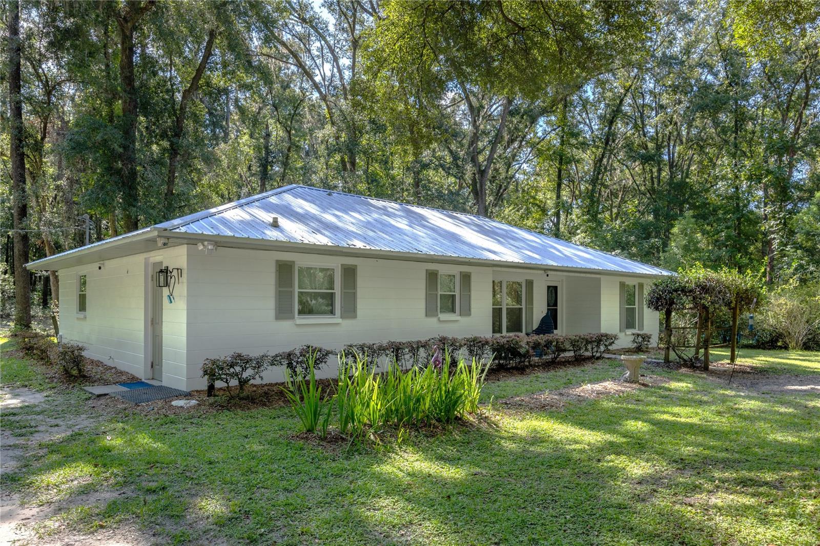 **Discover Your Nature Lover's Paradise!**
Step into tranquility with this charming 3-bedroom, 2-bath concrete block home nestled on 5 wooded acres teeming with vibrant forest life. This secluded retreat invites you to experience the beauty of nature right at your doorstep, surrounded by diverse wildlife and a rich variety of trees and lush vegetation.
As you enter, you'll be greeted by an open floor plan featuring cathedral ceilings, creating an airy and inviting atmosphere perfect for entertaining friends and family. The spacious kitchen boasts ample cabinets and counter space, making meal preparation a delight. A convenient eat-in peninsula adds additional seating and seamlessly complements the dining area for those intimate gatherings.
Retreat to the sizable primary bedroom, which includes a generous walk-in closet - perfect for all your storage needs. The attached primary bathroom features a tub/shower combo along with a linen closet for added convenience. Two roomy guest bedrooms provide comfort for visitors or family, while a substantial laundry room offers ample space to accommodate a freezer or second refrigerator.
Recent updates enhance this home's appeal, including a new roof, upgraded HVAC system, modern kitchen appliances, and stylish new LVP, flooring, porcelain tile, new lighting fixtures, security system. The freshly painted interior and exterior bring a bright, clean look to every room.
French doors lead you out to the picturesque patio where you can unwind and enjoy the sights and sounds of nature. Picture yourself relaxing as turkeys and deer wander by, or perhaps cultivating a new hobby in birdwatching as you observe owls and hawks grace your backyard oasis.
Situated privately at the end of a cul-de-sac on a one-way paved street, this home guarantees peace and quiet without through traffic. Despite its serene setting, this property is conveniently located near I-75, providing quick access to Lake City just minutes away and Gainesville in about 20 minutes.
If you cherish privacy and natural beauty, this home is your dream come true! Don’t miss out on this unique opportunity—call today to schedule your appointment and view this lovely property!