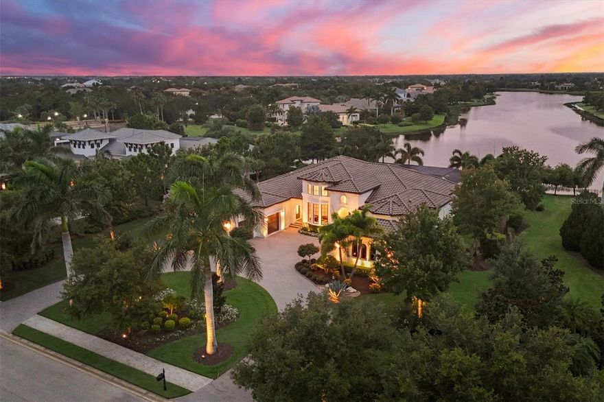 Discover unparalleled luxury at this magnificent lakefront estate in The Lake Club. Custom crafted by John Cannon Homes, this residence exudes elegance and sophistication with curated finishes and panoramic lake views. Situated on over half an acre of meticulously landscaped grounds, this home welcomes you with a circular drive and manicured gardens. As you step through the iron double front doors, you're greeted by voluminous ceilings, neutral wood-look porcelain tiles and 7.25-inch crown molding throughout. The solid eight-foot interior doors enhance the sense of grandeur, leading you to a formal dining/living room featuring a ventless stone fireplace surrounded by built-in cabinetry, perfect for cozy evenings. Entertain with ease in the gourmet kitchen, equipped with stainless steel Wolf, Sub-Zero and Asko appliances, dual sinks, quartz countertops and exquisite solid wood presidential-style cabinetry with soft-close dovetail drawers and under and over-cabinet lighting. A spacious oversized pantry provides ample storage, while the eat-in breakfast nook offers a serene aquarium window overlooking the lanai. A spacious great room off the kitchen with built-in dry bar is perfect for entertaining. The light-filled office boasts double French doors, soaring ceilings, built-in features and bay windows that capture natural light and inspiring views. Retreat to the expansive primary suite featuring tray ceilings, a generous seating area overlooking the pool, and custom dual closets designed for optimal storage. The ensuite bath is a sanctuary with a free-standing clawfoot tub, a modern Roman shower overlooking private garden views and water feature, creating a spa-like experience at home. Additional living spaces include three well-appointed bedroom suites, each offering comfort and privacy for guests. Step outdoors through 10-foot disappearing glass sliders to the large enclosed lanai adorned with travertine decking. Here, you’ll find a heated saltwater infinity pool with a sun shelf and spa, surrounded by plentiful outdoor areas and a full summer kitchen, ideal for alfresco dining against the backdrop of breathtaking lake vistas. This home is equipped with essential modern conveniences, including a whole-house generator, water filtration system, central vacuum system, and impact windows and doors, ensuring peace of mind and energy efficiency. Completing this unparalleled offering is a three-car side-entry garage with built-in cabinetry, providing ample space for vehicles and storage. Nestled in The Lake Club is an impressive 20,000-square-foot Grande Clubhouse, a hub of luxury amenities. Enjoy two pools, including a zero-entry pool with splash park, perfect for family fun. Indulge in poolside dining and unwind at the spa and fitness center offering guided workout classes, massages and facials by on-staff aestheticians. Sports enthusiasts will appreciate the tennis and pickleball courts with expert racquet pros available. Experience a vibrant social scene with a calendar filled with events. Inside the Grande Clubhouse, relax with billiards, pool tables, televisions, and game and card tables for various entertainment options. Cozy seating areas, a fireplace and an outdoor cigar lounge provide inviting spaces to socialize and unwind. Don’t miss the opportunity to experience luxurious lakefront living at its finest. Schedule your private tour today and imagine the possibilities awaiting you at this extraordinary address in The Lake Club.