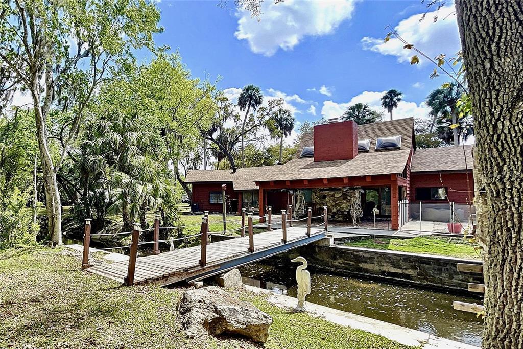 Two homes situated on over 16 park-like acres with a Spring Fed – 120 ft deep Lake (approx. 6 acres in diameter). This property is spectacular!!! The main home and guest/home #2 have the look and feel of a cozy cabin in the mountains. As soon as you walk in the main house thru the solid wood double front doors, you will fall in love with the Massive Great Room with its high vaulted ceilings made of Natural Pine, Tongue & Groove Wood and floor to ceiling stone, wood burning, fireplace, skylights and glass sliders leading to a covered back porch overlooking the most tranquil setting of a brook/stream and inground Plunge Pool with waterfall, LED lights and safety fence surrounding entire area. The Main house is 2674 sqft with 3 Bedrooms and 4 Baths, Kitchen boasts solid wood cabinets, red cedar countertops and bar/island. The oversized master bedroom has a vaulted ceiling, full bath with soaking tub and glass doors leading to a private screened porch. There are 2 a/c units, one unit is approx. 1 month old, the other is approx. 1 year old. New roof. The second house has the same mountain cabin feel with 1818 sqft of living space, 3 bedroom 2 baths, vaulted ceilings and indoor laundry room. The a/c unit is approx. 4 years old. There is also a garage and carport separate from the homes. Privacy galore but close to stores, restaurants, and a short drive to Florida’s beaches. True Paradise!