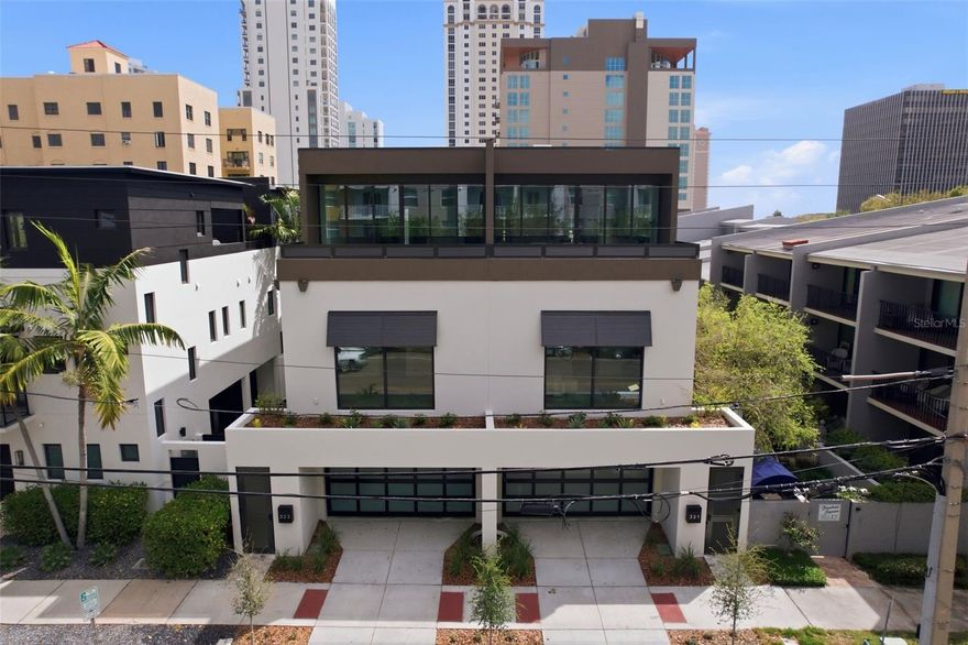 Welcome to 321 2nd St N in the heart of vibrant Downtown St. Petersburg—one of two truly remarkable, custom-designed townhomes by Next Design & Build. Offering 3 bedrooms plus a den, 4.5 bathrooms, a private elevator, and a 2-car garage, this three-story residence spans approximately 3,900 square feet of thoughtfully curated living space. Enter through your private front entrance to the first level, where a versatile flex space with a full bathroom offers the ideal setup for a home office, den, or can easily function as a fourth bedroom. This level also features a dedicated laundry room, access to a rear porch and backyard, and entry to the attached two-car garage. A custom elevator provides seamless access to all three floors. The second level is dedicated to the home’s sleeping quarters, including a spacious primary suite that serves as a true retreat, complete with a spa-inspired bathroom. Two additional generously sized bedrooms, each with their own en-suite bathrooms, offer comfort and privacy for family or guests. The third level is the showpiece of the home—an expansive open-concept living space designed for both everyday living and elevated entertaining. The chef’s kitchen features double islands, custom cabinetry by Stephen D. Fine Cabinetry, and a premium Sub-Zero and Wolf appliance package, including double ovens. A butler’s pantry enhances both form and function, while the living area opens seamlessly to a spacious balcony, perfect for enjoying fresh air and the energy of downtown living. A stylish half bath completes this level. Throughout the home, you’ll find high-quality finishes and thoughtful details, including hardwood flooring by Integrity Flooring, luxury tile and quartz surfaces, trimless doors, and impact-rated ES windows and doors, including the garage door. A striking wraparound staircase with glass railings and a custom elevator serve as both functional elements and architectural focal points. Comfort is ensured year-round with three LG 19 SEER A/C systems, providing efficient, zoned climate control. A rare opportunity to own a one-of-a-kind luxury townhome in one of St. Petersburg’s most sought-after locations, just moments from downtown dining, waterfront parks, and city amenities