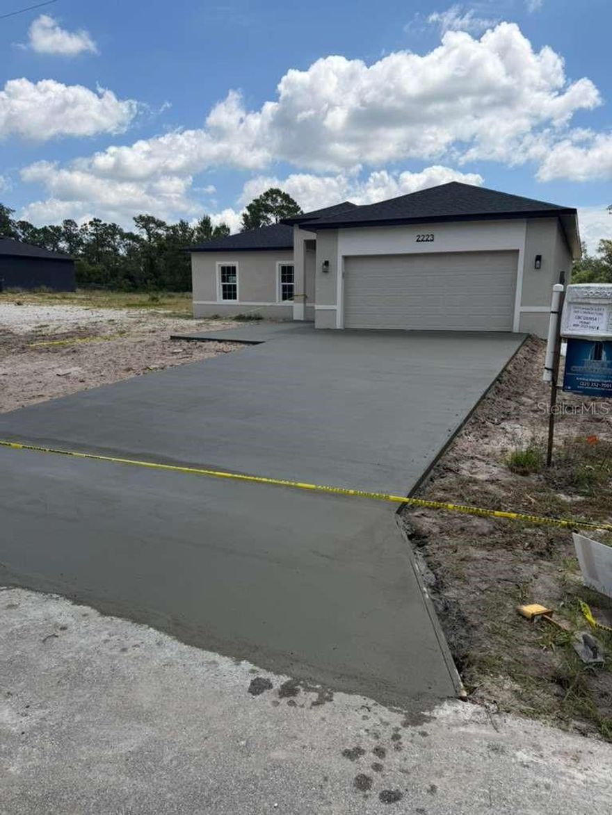 Under Construction. Brand new construction, never lived in! Welcome to 2223 Lemon Dr, Lake Wales, a 4-bedroom, 2-bathroom home where contemporary design meets quality craftsmanship. The open-concept great room flows into a chef's kitchen featuring quartz countertops, a wood slat waterfall island with undermount sink, stainless steel appliances, flat-panel white cabinetry with matte black hardware, designer tile backsplash, and a spacious walk-in pantry. LVP flooring runs throughout. The primary suite is a true retreat: dual quartz vanity with double undermount sinks, matte black fixtures, wood slat accent wall, designer mirrors, and a walk-in tiled shower with hex mosaic floor and built-in shelving. The second bath features a full tub/shower combo with tiled surround and sliding glass door. Three additional bedrooms all include closets. Designer touches throughout include track and pendant lighting, a full-wall wood slat accent in the living area, and an oversized 2-car garage with epoxy-coated floor. No HOA. Driveway forming in progress — nearly complete. Be the first to call this one yours!