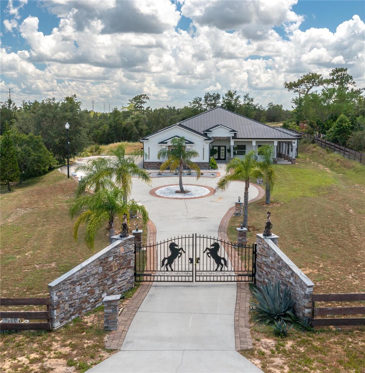 FOR SALE - Stunning 4 bedroom/4 bath Single-Family Home in Haines City on an acre of land.  This beautiful SMART home was built in 2025 and comes with all of the latest appliances, light fixtures, you name it! The ceilings are 13'8" in the Great Room and in the Kitchen. The Great Room area measures 17'x30'. The Kitchen has top-of-the-line stainless steel General Electric appliances with a matching stainless steel range hood. The Kitchen has a deep, stainless steel sink to match the appliances. The 42" Kitchen cabinets are made of real Pinewood. The Kitchen features gorgeous Black Galaxy granite countertops. The windowsills throughout the house are also made of the Black Galaxy granite. All of the lighting is LED throughout the house with inset caster lights in the ceiling and beautiful, contemporary chandeliers and light fixtures. The lights in the Great Room and the Kitchen can change color to compliment the mood of any occasion. The Dining Room also has beautiful light fixtures and a built-in Coffee Bar. For the rest of the home, the ceiling height is 10'4" with 8' interior doors. The flooring throughout the home is a beautiful marbled porcelain tile.  The Primary Bedroom is a generous size and has two walk-in closets and a built-in bookcase. There are also two linen closets for extra storage. The ceiling fan in the Primary Bedroom is 10' wide and compliments the decor. The Primary Bathroom has a Garden Tub with water jets, two shower heads and a shower tile that beautifully compliments the rest of the decor. Two of the Bedrooms have access to the outdoors with a nice overhang giving them their own private entrance. All of the bedrooms have contemporary ceiling fans. All of the Bathrooms have glass shower doors and massage stones for the shower floors. The fourth Guest Bathroom is conveniently situated right outside the Kitchen. The lighting in the house is inset in the ceiling with caster lighting and gives it a very elegant look. There are light posts on the outside of the house in the driveway along with inset lighting in the driveway pavers. The house has its own gate code for entry and the property is fenced with wood horse fencing. The house has a huge, enclosed lanai ideal for entertaining and is built with open verandas all around the house. The Garage is massive and has a huge, deep stainless-steel sink. As far as energy saving features go, this 5-Star Energy home has wonderful features such as: a Metal Roof, 18 Sear 5-ton A/C unit, 50 Gallon Hybrid Water Heater, SMART Thermostat, Fire retardant paint in the attic, Lightning Rod protection, Foam Insulation in the attic, and Double-pane windows. Come see this spectacular home today.
