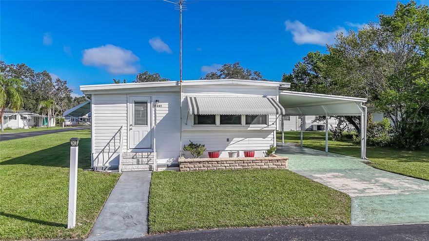 Beautiful Corner Lot in Tropical Mobile Park! Discover this charming nicely maintained 1966 mobile home with additions and two storage sheds  — offering plenty of space and functionality in a small community. Step through the front door into a fully furnished home where the spacious living room welcomes you with built-in bookcases and flows seamlessly into the dining area and kitchen. The dining room includes built-in corner cabinets and a dining set, while the kitchen is equipped with a refrigerator, range, dishwasher, and ceiling fan — everything you need to move right in, plus there are three Televisions that convey! The primary bedroom is large and features laminate flooring and three closets with the primary bathroom in the hallway that has with a walk-in shower and a built-in, pull down bench for added comfort. A second bedroom is also large and has two closets could also serve as the primary suite. Step outside to the carport area, where you’ll find two sheds — one with a washer, dryer, and utility sink, and another for your gardening tools and storage. Additional features include Roof-over, shutters, mostly updated windows, blinds, and move-in ready furnishings. Community amenities include a clubhouse and shuffleboard courts for your enjoyment for a low annual fee of $210. The seller will cover the $500 road maintenance buy-in fee for the buyer — a fantastic value! Don’t miss this opportunity to own a lovely home on a prime corner lot in the sought-after Tropical Mobile Park. Call today to schedule your private showing — this one won’t last!