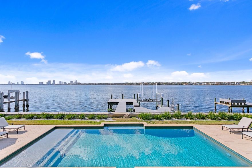 Experience unparalleled luxury in this breathtaking Davis Islands estate, where waterfront grandeur meets timeless elegance. Nestled on a coveted 100-foot-wide lot along the open bay, this British West Indies masterpiece by Windstar Homes offers unobstructed panoramic water views, mesmerizing sunsets, and a dazzling backdrop of Bayshore Boulevard and Downtown Tampa’s shimmering skyline. Located on Adalia Avenue—one of the island’s most sought-after addresses—this estate sits in a premier location known for record-breaking home sales. One of the few streets offering true walkability, it provides effortless access to Downtown Tampa, Water Street, Amalie Arena, and the scenic Riverwalk. A gracious entry, framed by an expansive paver drive and lush landscaping, welcomes you into a home designed to showcase breathtaking bay views from nearly every room. The thoughtfully designed interior features grand living spaces, including a formal living/great room, elegant dining room, chef’s kitchen with a breakfast area, executive office, and a warm, inviting family room on the first level. Exposed wood beams, rich hardwood flooring, multiple fireplaces, impressive architectural elements, and statement lighting elevate the home’s refined aesthetic. The chef’s kitchen is designed for effortless entertaining, boasting professional-grade appliances, a generous island with a prep sink, custom cabinetry, a beverage center, and arched French doors leading to an inviting covered outdoor gathering space. A private executive office/library, adorned with rich wood paneling and built-in bookshelves, offers a serene retreat with bay views and access to a tranquil courtyard. Upstairs, the impressive primary suite retreat delivers breathtaking water views, French doors opening to a private terrace, a spa-inspired en-suite bath, and spacious walk-in closets. The upper level continues with three additional en-suite guest bedrooms. A separate suite includes a loft, sitting area, private entry staircase, and a fifth ensuite bedroom—ideal for guests or multi-generational living. The ultimate in resort-style waterfront living awaits outdoors, where an expansive terrace, covered lounge, outdoor kitchen, and lush landscaping surround an elegant pool and a generous waterfront deck. A private dock with a lift provides seamless access to open water, inviting you to embrace the premier boating lifestyle. Whether hosting a grand soirée or an intimate gathering, this estate is designed for luxurious entertaining with numerous indoor and outdoor spaces, gracious waterfront terraces, manicured grounds, and breathtaking sunsets. Situated in one of Tampa’s most exclusive waterfront communities, residents enjoy an array of recreational options, including a sailing and yacht club, tennis complex, community pools, and Davis Islands Village. With A-rated schools, proximity to championship sports venues, and the world-class shopping, dining, and entertainment of Water Street, this extraordinary estate offers the pinnacle of coastal luxury living.