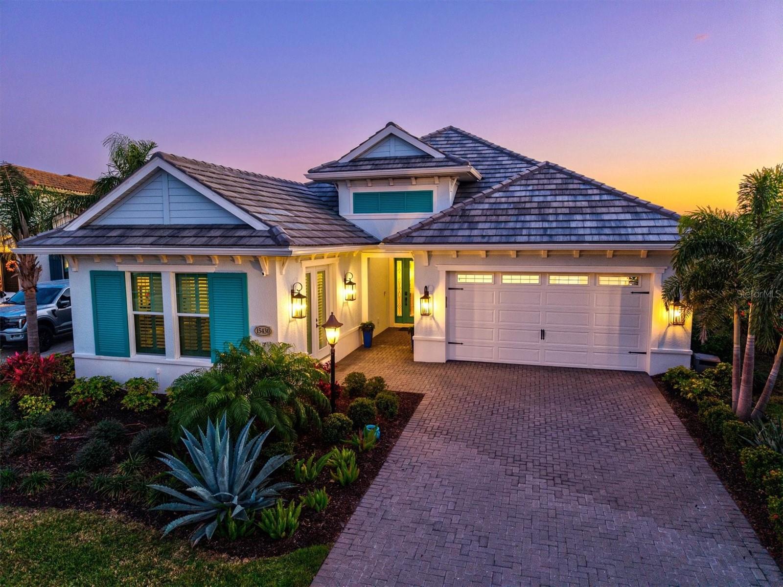 Discover a realm of unparalleled craftsmanship with this enhanced Carlotta model by Neal Signature Homes, a true architectural marvel boasting over $300,000 in opulent upgrades. Nestled within the guard-gated enclave of Country Club East in Lakewood Ranch, this estate redefines luxury living. From the moment you arrive, the home’s stately British West Indies elevation captivates with its striking symmetry, pristine coastal color accents, and elegant architectural detailing. The Thermatru Smooth-Star entry door with Blackstone caming and impact-rated sidelights opens to reveal an awe-inspiring interior where soaring double recessed foyer ceilings perfectly paired with two palacio pendants set the stage for sophistication. At the heart of this distinguished residence is a culinary masterpiece of a kitchen. Here, top-of-the-line cabinetry with 18-inch stacked uppers, stunning quartz countertops, and a full-height designer backsplash create a striking backdrop for the GE Café appliances. A sprawling premium quartz island commands attention, complemented by custom soft-close drawers, integrated roll-out shelving, and pot-and-pan storage. The grandeur continues into the expansive great room, where a coffered ceiling and ambient recessed lighting offer an atmosphere of refined elegance. Walls of impact-resistant glass open to an extended covered lanai, a breathtaking outdoor retreat designed for lavish entertaining. A fully equipped summer kitchen with a gas grill and prep space pairs beautifully with the custom-designed Waterscapes saltwater pool, featuring a panoramic cage, travertine pavers, and tranquil water features; an idyllic sanctuary that transforms every moment into a resort-style experience. The owner’s suite is a private sanctuary. A gracious two-foot extension creates an intimate sitting area with direct access to the lanai. The spa-inspired ensuite offers a symphony of luxury with a custom glass-enclosed shower, built-in makeup vanity, and striking quartz surfaces, signature cabinetry and exquisite tilework. The club room, enhanced with upgraded wood flooring, presents a versatile retreat; perfect for a media lounge or refined entertaining space. One of the home’s most remarkable enhancements is the conversion of the three-car garage into a spacious fourth bedroom with private entry, complete with a three-foot extension. Whether used as a guest suite, private office, or secondary living space, this addition enhances the home’s livability without compromising its grandeur. Every detail of this estate has been meticulously curated, from the insulated garage doors and garage extension to the Tempus smart home automation system, featuring in-ceiling speakers, 2MP IR turret security cameras, and a fully integrated wireless security system. Set amidst Lakewood Ranch’s most coveted community, this estate offers exclusive access to world-class amenities like a private clubhouse, resort-style pool, a premier fitness center, and miles of scenic walking trails. Lawncare is also included with the HOA. Additionally, you have the privilege of joining the elite Lakewood Ranch Country Club, where you can indulge in championship golf, spa services, exquisite dining, a state-of-the-art fitness center, and premier racquet and pickleball courts; all within a setting of unmatched elegance and prestige. This is more than a residence; it is a statement of prestige, refinement, and uncompromising luxury.