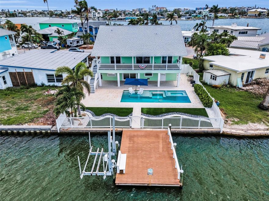 Spectacular ultra-contemporary Key West–style elevated waterfront estate perfectly positioned on wide-open Boca Ciega Bay, offering commanding 180-degree water views and direct, effortless access to the Gulf. This is true front-row coastal living—where open water, expansive skies, and refined design converge.
Designed for seamless indoor-outdoor living, the deep, full-length waterfront porch captures breathtaking sunsets and constant water activity. The private resort-style salt water pool is both heated and cooled and features a sun shelf, oversized spa, and dine-in swim-up table—creating a serene yet social retreat. An oversized dock with 13K boat lift and built-in seating sits directly on wide-open bay waters, ideal for boating, entertaining, and daily dolphin visits.
Inside, the home has been completely renovated with an open, sun-drenched layout crafted for luxury living and entertaining. The great room showcases custom beamed ceilings and a designer electric fireplace with programmable lighting, anchoring a space that is both warm and striking. The chef’s kitchen is a true centerpiece, featuring a large social island, custom navy and white shaker cabinetry, induction cooktop with vented hood, stainless steel appliances, and generous prep space. A custom wet bar and beverage station with dual-zone beverage center, wine refrigerator and mounted television seamlessly connects the living spaces.
The primary suite is a refined coastal sanctuary with a custom shiplap beamed ceiling and spa-inspired bath offering a dual rainfall shower, dual vanities, and a spacious walk-in closet. Two additional bedrooms share a Jack-and-Jill bath, while the waterfront guest suite enjoys panoramic bay views and a private en-suite—perfect for hosting in comfort and style.
The lower-level parking area provides both ample space and convenience, featuring an elevator that offers direct access to the main living area. This thoughtful design ensures ease of entry for both residents and guests, regardless of the weather or time of day.
Several luxury upgrades further enhance the home’s appeal. Tesla solar panels and an EV charging outlet cater to modern, eco-conscious lifestyles. Elegant flooring extends throughout the entire residence, complemented by solid-core interior doors and custom millwork, which contribute to a refined and cohesive interior aesthetic. For added functionality, the home includes a dedicated indoor laundry area. Smart-home integrated exterior lighting provides both security and ambiance, seamlessly blending technology with stylish outdoor living.
 
 Located just blocks from the white-sand beaches of Madeira Beach in Bay Point Estates—one of Pinellas County’s most prestigious waterfront communities.