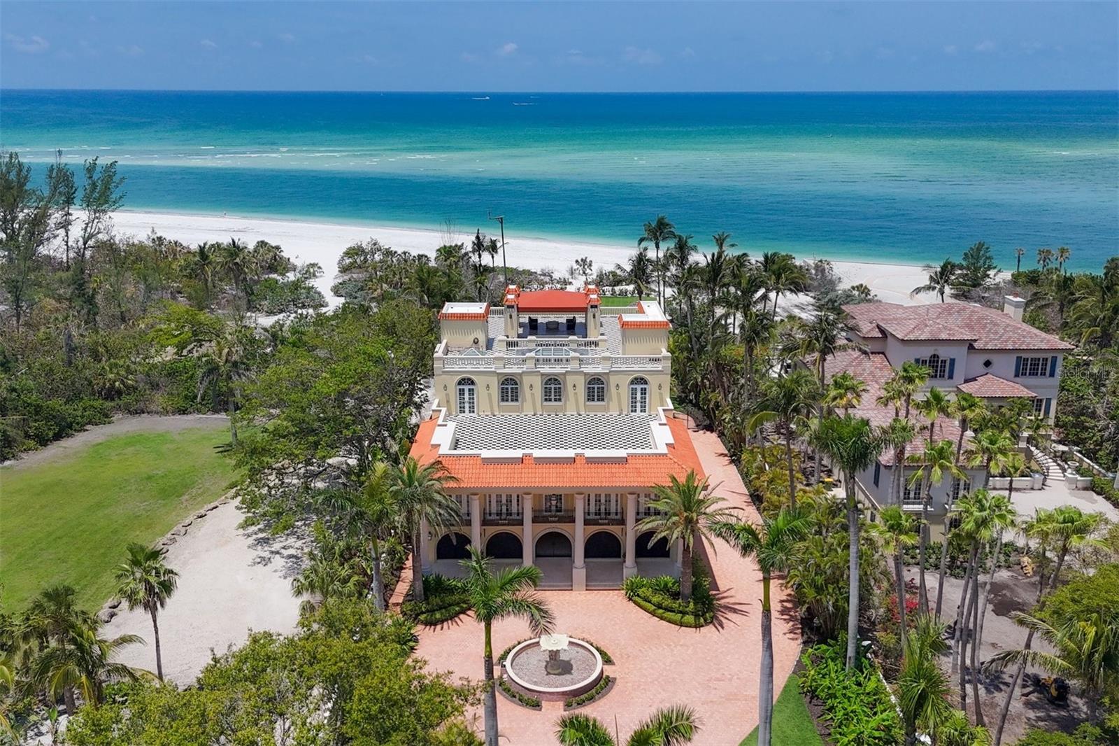 Along the iconic shores of Lido Key Beach, 1067 Westway Drive stands as a beacon of comfortable and sophisticated coastal living. Every detail has been meticulously curated to create an exceptional lifestyle situated on an extraordinary property in an extraordinary home. As you step into the sun-soaked atrium foyer, you are immediately greeted by the grand staircase made of travertine and adorned with custom railings. This entrance sets the casual tone for the rest of the home, where every room is a masterpiece of design and craftsmanship. The great room is a wonderful space, with its soaring ceilings, intricate moldings and stone fireplace. Floor-to-ceiling windows and doors offer panoramic views of the Gulf of Mexico, access to an enormous terrace and endless sunsets. This space is seamlessly connected to the bar and lounge, equipped with a glass-enclosed wine room with space for 500-plus bottles, creating a space that is ready to host friends and family. Adjacent to the lounge is a sunroom with glass walls that fill the room with natural light, creating a serene space to relax and unwind. The gourmet kitchen is a dream, boasting an enormous center island with seating and storage, granite counters, two sinks, two dishwashers, a Wolf® induction cooktop and a Dacor® range with six burners. Customized pullouts in the cabinetry and custom designed pantries ensure everything is organized. There is also an informal dining area enveloped in large banks of windows and doors providing access to the terrace and framing the best views. The adjacent dining room is the perfect setting for intimate dinners or lavish gatherings, with plenty of seating and a custom tray ceiling. Outside, the grounds are an oasis, with lush Florida landscaping, multiple covered and uncovered seating areas, a custom infinity-edge pool with intricate tile design, and multiple roof decks. One of the highlights of this home’s outdoor entertaining spaces is the rooftop deck, ready for hosting events with the well-equipped kitchenette and bath, and plenty of space for dining, dancing and enjoying the sunset over the Gulf of Mexico or the sunrise over Sarasota Bay and downtown Sarasota. The primary bedroom suite is a sanctuary of luxury and comfort, with its own private terrace overlooking the sparkling waters of the Gulf of Mexico, an adjacent exercise room and access to a front terrace. The resort-like en-suite bath is a work of art, with its dual vanities, oversized soaking tub with marble surround and enormous windows, and an indoor-outdoor marble walk-in shower. The custom organized closet offers a central storage island, abundant space for clothing, shoes and accessories, and its own private laundry room. The guest suites are retreats, each with their own en-suite bath, custom-organized spacious closet, plantation shutters, and high ceilings with crown molding. Some offer terraces with lush views of the property and beyond. Additional features include a movie theatre, a fitness room, access to the second rooftop deck, a stunning office with custom built-in storage and an additional family room, game room and bunk room. With its unrivaled location, exquisite design and unparalleled amenities, 1067 Westway Drive is more than just a home, it is the ultimate in beachfront living.