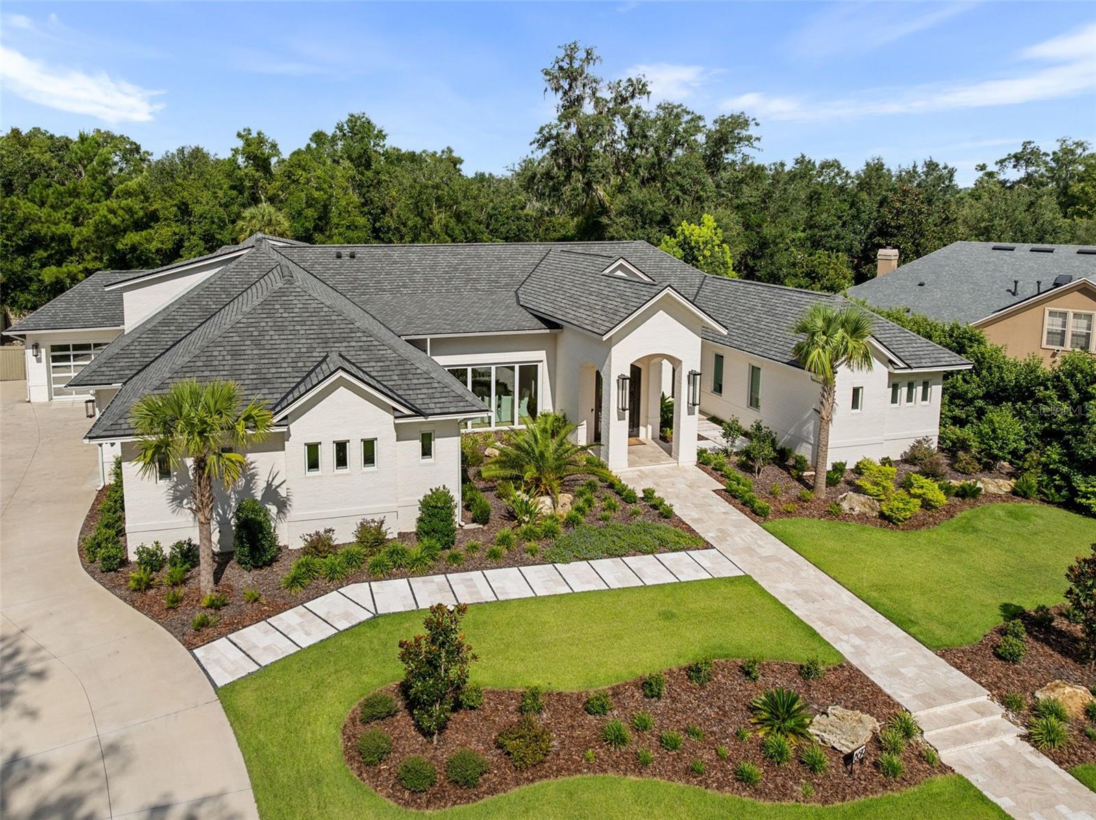One or more photo(s) has been virtually staged. Experience the pinnacle of luxury living in this stunning, custom-built masterpiece in the highly sought-after Branton Court of Haile Plantation. With an impressive 6,937 sq ft of heated/cooled living space and an additional 572 sq ft of climate-controlled unfinished space, this exceptional residence blends timeless design, modern innovation, and superior craftsmanship. Constructed with energy efficiency and longevity in mind, the home showcases ICF construction, classic brick exterior, and an extended-life roof, delivering both durability and refined curb appeal. Step through grand, custom-forged iron doors into an expansive open-concept layout, bathed in natural light from dramatic, oversized windows that frame views of the lush surroundings. This architectural gem offers 6 generously sized bedrooms, 4 luxurious en-suite full bathrooms, and 2 half baths, all thoughtfully designed with both comfort and elegance in mind. The home’s interior is enhanced by rich, wide-plank wood floors that flow gracefully throughout the main living areas, adding warmth, sophistication, and timeless elegance. This home also includes a rare and fully handicap-accessible private casita with its own spacious bedroom and spa-like en-suite bathroom—ideal for guests, in-laws, or live-in caretakers. The heart of the home is a gourmet chef’s kitchen, equipped with top-of-the-line Wolf and Sub-Zero appliances including an induction cooktop, double ovens, steam oven, warming drawer. Custom Busby cabinetry adds richness and functionality, while the stylish wet bar features a second dishwasher, ice maker, and wine refrigerator. For the ultimate entertaining experience, the residence is equipped with a premium built-in surround sound system, delivering high-fidelity audio throughout key living spaces. Tucked behind the cabinetry, discover a spacious walk-in hidden pantry, offering abundant storage, discreet organization, and a touch of luxury that blends seamlessly with the kitchen’s clean, elevated design. Unwind in the versatile bonus room, ideal for a media lounge, home gym, or playroom. Advanced home technology includes the Moen Flo Smart Water Monitor and Shutoff System, offering 24/7 leak detection and remote water control for ultimate peace of mind. Enjoy a quiet evening under the covered patio with a fully equipped summer kitchen. This expansive outdoor cooking area features a professional-grade grill, flat-top griddle, and generous counter space. Every inch of this estate has been meticulously curated with premium finishes, designer details, and custom features that set it apart. This home offers an unparalleled lifestyle of comfort, sophistication, and lasting value. Don't miss the opportunity to own one of Haile Plantation’s most distinctive and desirable luxury homes.
