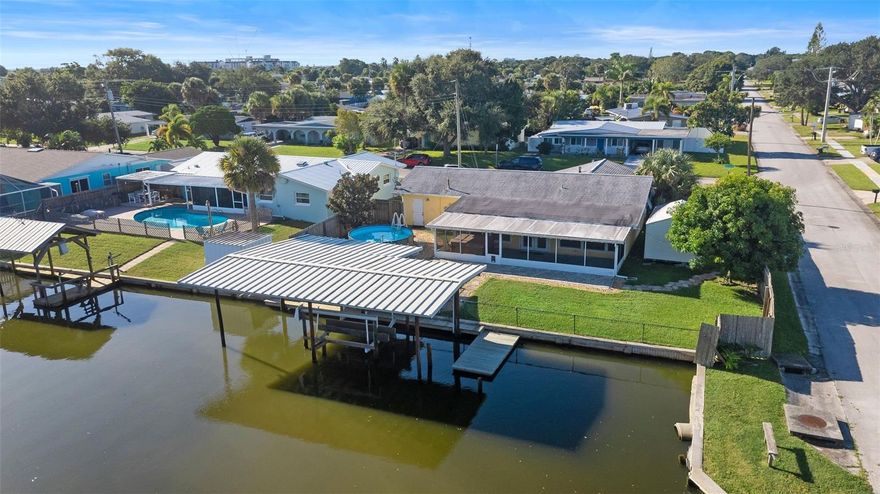 Waterfront Paradise! Located on a deep, navigable canal to Sykes Creek, this immaculate concrete block home is a dream for boaters, entertainers, and AirB&B investors! Enjoy breathtaking sunrises and sunsets from your oversized covered dock with lift, dining area, and room to relax while watching dolphin and manatee. The bright, open layout features two spacious master suites: one with a remodeled bath and a bonus room perfect for a game or family room. New luxury vinyl plank flooring (2025) in all bedrooms and Florida room. Main master includes a walk-in closet and direct Florida room access. Outdoors, enjoy a fenced corner lot, large screened patio in a lush tropical setting. Community waterfront park with tennis, basketball, and playground. No HOA! Centrally located in Merritt Island, ideal for full-time living, winter escape, or vacation rental!