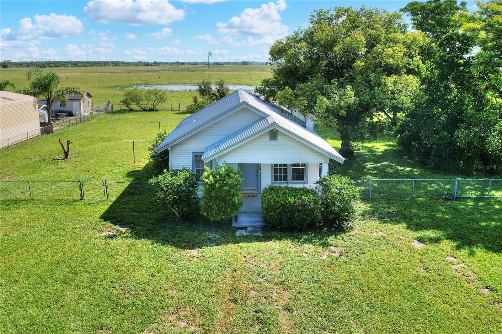 This charming 1924 frame home, nestled on nearly half an acre in West Lake Wales, Florida, offers a blend of historic character and modern convenience.
This cozy 2-bedroom, 1-bath home features a durable metal roof and comfortable central air conditioning, with a new 3-ton AC system installed in 2023. For your peace of mind, the entire home was rewired with new electrical in 2020.
The large room in the back of the home has historically been utilized as the primary bedroom, offering a spacious and private retreat. A separate dining room (with closet) provides a dedicated area for meals. The kitchen comes equipped with a refrigerator, built-in oven, and cooktop. A washer and dryer are also included. The bathroom features a single vanity and a tub/shower combination.
Enjoy the expansive outdoor space, fully secured with a chain-link fence. There's plenty of room to add your own garden, and you can take advantage of the impressive 11x24 shed, perfect for storage or hobbies. This property operates on a private well and septic system, offering independence and lower utility costs.
Situated between the thriving communities of Bartow and Lake Wales, you'll enjoy easy access to the amenities and attractions of both cities, including historic downtowns, local events, and various recreational opportunities. The bordering property in the rear is a peaceful cattle pasture, offering a serene backdrop.
Call your Realtor today to schedule a showing!