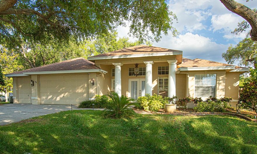 Rare opportunity to live in the highly desirable Country Woods Neighborhood within Palm Harbor/Dunedin. Beautifully kept home features 2781 square feet of generously open concept living spaces that includes a practical split floor plan: with 4 large bedrooms and 3 full baths, all freshly updated and painted.

Your future home is situated on a large corner lot surrounded by 6 mature live oaks and magnolia trees which looks stunning at night with automatic dusk-to-dawn landscape lighting. A grand entrance opens to a welcoming great room with a double-sided see-through stacked stone gas fireplace with a view of the lanai and pool beyond. Upgraded porcelain wood plank-textured tile floors (2025) continue throughout the entire house. A cooks kitchen features upgraded GE Monogram gas cooktop and smart oven. All stainless steel appliances are less than a few years old and convey. The oversized granite kitchen island is perfect for family and entertaining and the main living area has a 15 foot wide feature wall with custom built in cabinets creating plenty of clutter-free storage. Enjoy indoor/outdoor living with multiple sliders that open to a paver lanai and a custom salt water swimming pool covered with a new (2025) pool cage. The backyard surrounding the pool is completely fenced for your family and pets.  The primary bedroom has a freshly updated en-suite bath with a free standing soaker tub and oversized shower. A second bedroom also has an en-suite bath with a separate entrance to the lanai and pool. Two other large bedrooms share an updated bath. All are freshly painted. Eight pocket doors throughout the house make great use of doorway space. Plantation Shutters and custom blinds let you control the light and privacy.
Three garage spaces and an oversized driveway provide ample parking and convenience for family and friends. Recent improvements include a new AC system (2026) , Pool Enclosure (2025) Primary Bath update (2026). Country Woods is less than a mile to the Dunedin Causeway and Honeymoon Island State Park, The Pinellas Trail for walking and biking, close to shopping, healthcare and less than 35 minute to Tampa International Airport.