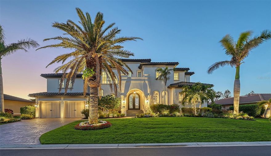 Enter a world where elegance meets functionality in this John Cannon custom-designed 5-bedroom, 5.5-bathroom coastal inspired Spanish Mediterranean masterpiece, offering 4,117 square feet of refined coastal living. Designed for the most discerning buyer, this gorgeous residence is in the exclusive Country Club Shores IV community, on south Longboat Key, seamlessly blends contemporary finishes with timeless architectural details, creating a home that is both inviting and luxurious. A striking arched double iron door welcomes you into the grand foyer, setting the tone for the exquisite craftsmanship found throughout. The soaring coffered ceilings in the great room, complemented by a warm fireplace, create an atmosphere of sophistication and comfort. As you move through the open concept living space, walls of sliding doors blurs the line between indoor and outdoor living, offering breathtaking canal views and effortless access to the outdoor entertainment areas. Built with Superior craftsmanship , the all-block and concrete construction, along with impact glass, ensures lasting durability. The home’s interior is a masterclass in modern coastal design, incorporating a palette of grays, whites and periwinkle expertly curated by award-winning Sarasota designer Micheline Laberge, ASID. Grays and whites serve as the foundation, allowing bold colors, stunning fabrics, and artistic prints to enhance each space. The collaboration is just magical throughout this exquisite property. The first-floor primary suite is a sanctuary bathed in natural light, featuring a stunning stepped illuminated ceiling accented with gauntlet gray paint and luxurious Maple flooring. The bathroom is a true work of art, where bronze brocade tiles, enriched with a play of light and shadow, frame a floating oversized shower and a statement soaking tub creating an ambiance of pure indulgence. Crystal sconces embellish the mirrors & create warmth to set the mood for relaxing.  The gourmet kitchen is a chef’s dream, featuring an oversized island with additional seating & storage, custom solid maple cabinetry painted white with pewter glaze, and stunning Bianco Antico granite countertops. A custom-made hood is framed by eight-panel glass cabinets, while a three-dimensional geometric Moon Onyx tile backsplash adds depth and movement. The same Bianco Antico granite extends to the charcoal-stained island cabinetry offering a striking contrast. The elegant dining room easily transforms for more casual alfresco dinners w/ the easy opening sliders to overlook your stunning water views. Designed for entertaining, the expansive outdoor area is spread across three levels. The main level boasts a spacious lanai, while a luxurious spa cascades into a resort-style pool on the second level. A fire pit and deck lead to a private dock equipped with a boat lift, offering easy access to the bay and beyond. The upper level is home to a spacious game room, designed w/ additional soundproofing for privacy, and 2 en-suite bedrooms, 1 separate guest bedroom with an evening terrace and a hallway ¾ bathroom, each thoughtfully crafted & exquisitely decorated for comfort and style. Midway between the first and second levels, a grand private en-suite bedroom provides an exclusive retreat for guests. This Stunning home is a testament to superior design and craftsmanship, offering the perfect balance of luxury, functionality, and coastal charm. Prepare to be “Wowed” come live the Dream now!