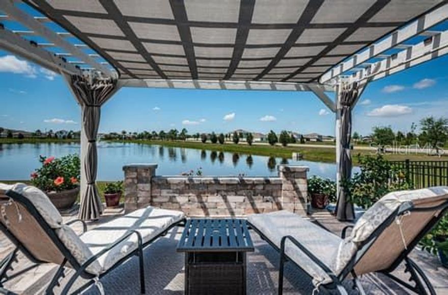 Discover the ideal blend of elevated style, comfort and nature in this exceptional 4-bedroom, 2.5-bathroom home located on a premium lot with serene pond views just around the corner from the 2 sprawling community pools and amenities center. Imagine beginning your day with a cup of coffee or relaxing in the evening with a glass of wine enjoying the sunset from your BREATHTAKING 750 SQUARE FOOT PAVER PATIO with SHADED PERGOLA, solar lighting, grilling area and fire pit. Designed for both relaxation and functionality, this home offers a chance to live the Florida Life in one of the area’s most desirable communities. Inside, you’ll find a spacious open-concept floor plan filled with natural light. The main living area creates an inviting setting for everyday living and entertaining. The kitchen features a large center island, granite countertops, and solid wood cabinets perfect for both cooking and gathering. Additional upgrades include crown molding, ceiling fans, designer lighting, additional cabinetry in the baths and laundry, and stained concrete flooring in the garage. Located just minutes from a variety of shopping and dining in an exceptional up and coming town center. Don't miss this opportunity to own a move-in ready home in a thriving community where style and luxury meets convenience and comfort!