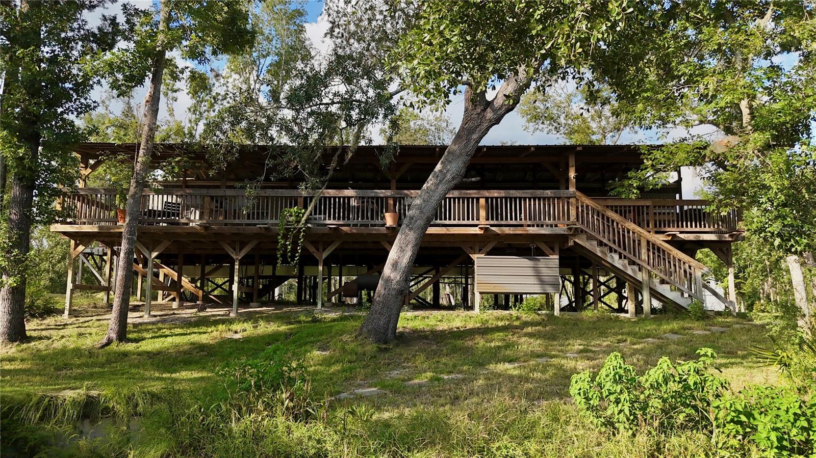 Located along the banks of the Withlacoochee River, this Hamilton County property offers a versatile mix of cleared acreage, hardwoods, and improvements that make it suitable for homestead living, recreational use, or small-scale agricultural activities. The property features a renovated two-bedroom, two-and-a-half-bath manufactured home that has been elevated and improved for comfort and durability. The residence includes a large back porch designed for entertaining, complete with an outdoor kitchen equipped for preparing meals for multiple guests. The front porch also provides additional outdoor living space. The acreage itself has been cleared and improved to provide a blend of open pasture and hardwoods, allowing for both agricultural use and recreational enjoyment. The layout and improvements make nearly all parts of the property accessible. Additional structures include a pole barn with RV storage, tractor parking, and two levels of tool storage. A dedicated chicken coop, an additional storage shed, and a fenced garden area support homestead or hobby farm activities. The property also has two RV hookups, providing opportunities for extended family visits or group gatherings. The land offers just under 1,000 feet of river frontage, creating a natural setting with abundant recreational opportunities. Across the river lies Twin Rivers State Forest, which expands the possibilities for hunting, hiking, camping, and fishing. Wildlife, including whitetail deer and wild turkey, is common in the area, providing opportunities for outdoor activities directly on the property. This property consists of two parcels and is accessed by a deeded easement. With its mixture of pasture, hardwood stands, river frontage, and on-site improvements, the land provides a unique opportunity for those seeking a manageable homestead or a recreational retreat. Nearby recreation areas include Twin Rivers State Forest (0.1 miles), Twin Rivers Wildlife Management Area (7.7 miles), and Blue Spring State Park (8.2 miles). The property is also within reasonable driving distance of nearby towns, including Jasper (approximately 15 miles), Live Oak (approximately 22 miles), and Madison (approximately 25 miles). These nearby towns provide access to supplies, schools, and services while maintaining the property’s private setting along the river. Whether used for a small farm, as a riverfront homestead, or as a recreational getaway, this Hamilton County property provides an accessible location with a strong mix of agricultural and outdoor features. Its improvements and existing infrastructure support a range of uses without requiring extensive setup, offering a ready-to-use opportunity along one of North Florida’s scenic rivers.