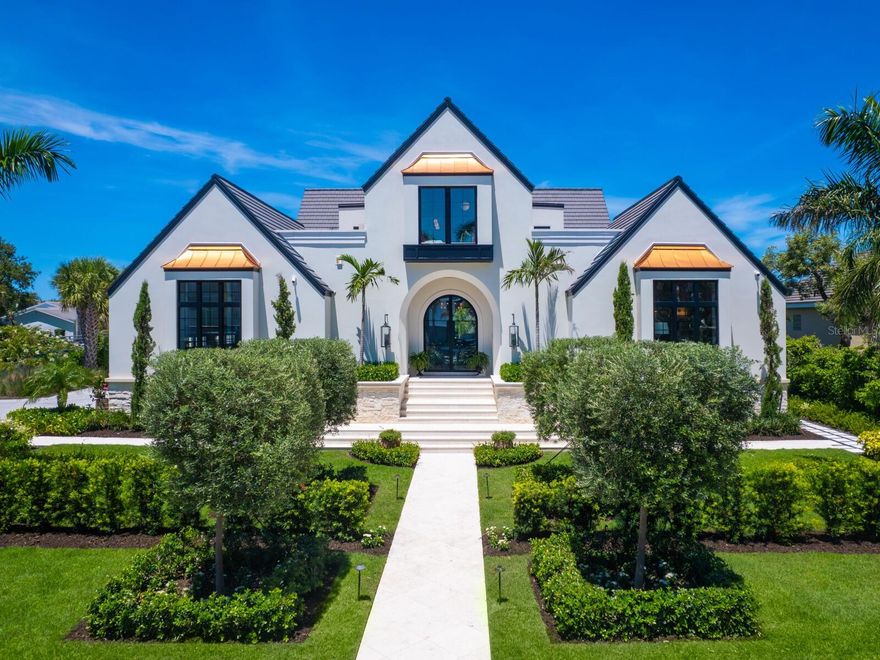 A breathtaking fusion of architectural brilliance and design sophistication, 440 Meadow Lark Drive is arguably the finest residence ever constructed in Sarasota. Envisioned by the masterful minds of architect Clifford Scholz and Voigt Brothers Construction, this custom estate is a testament to elevated living where no detail has been spared. From the moment you approach the bespoke exterior elevations, crafted to distinguish with striking individuality you realize this is not merely a home, but a work of art. Step inside to discover nearly 7,000 square feet of flawlessly curated interiors where each room tells a story.  Italian oak floors, Gucci, Phillip Jeffries, and Holly Hunt wallpapers, and SAWW’s custom cabinetry set the tone for refined elegance. Every room is inspired by the glamor of Kelly Wearstler’s Hollywood Regency style and brought to life by renowned designer Christiana Engert, while the entire home functions as a smart residence, seamlessly blending intuitive technology with timeless luxury. At the heart of the home, the kitchen is both showpiece and workspace, featuring Dolomite marble counters with protective tough-skin, double dishwashers, Wolf, Sub-Zero, and Miele appliances, and a hidden pantry with display cabinetry, wine chiller, and artwork. The adjacent morning room is perfect for casual lounging, complete with custom cabinetry and a discreet TV. The living room exudes warmth with a Nero Marquina marble gas fireplace, generous seating, and captivating water views, while the dining room stuns with a one-piece luxe side table and a dramatic custom chandelier. Entertain effortlessly in the media room with surround sound, three TVs, and a custom bar.  An adjacent butler’s pantry includes an additional refrigerator, washer/dryer, dishwasher, and concealed storage.  The 1400+ bottle wine cellar is a masterpiece unto itself.  With custom artistic designs, backlit lighting, and a commercial capacity cooling system, the one-of-a-kind space is perfect for the most discerning collector.  The primary suite is a sanctuary of indulgence with hand-painted wallpaper, sweeping waterway views, and his-and-her closets with exquisite built-ins, chandelier, a marble island, and boutique-style jewelry displays. The spa bathroom features gold-leaf inspired tile, dual vanities, and indoor and outdoor showers. Ascend the single-piece staircase to the upper level, where guest suites are equally impressive with vaulted ceilings, en-suite baths, and private access to the second-floor entertainment terrace. A loft with clerestory windows, serving bar, and hidden storage provides flexibility as a guest lounge, office, or retreat. A separate-access guest suite doubles as an office or bonus room, with its own bath and dramatic architectural lines. Outdoors, resort-level amenities await. The lanai offers seamless indoor-outdoor flow through oversized sliders, a full outdoor kitchen, fireplace, and multiple seating areas beneath tongue-and-groove ceilings. Limestone pavers surround a saltwater pool and spa designed for comfort and elegance, while a 20,000 lb boat lift and 7,000 lb deck lift for kayaks or paddleboards make this an ideal waterfront escape. Stunning privacy landscaping by Michael A. Gilkey ensures serenity across the grounds. With concrete walls on both levels, an 8-inch concrete slab second floor, full-house generator, whole-house water softener, and natural gas, this estate combines enduring structure with breathtaking beauty.