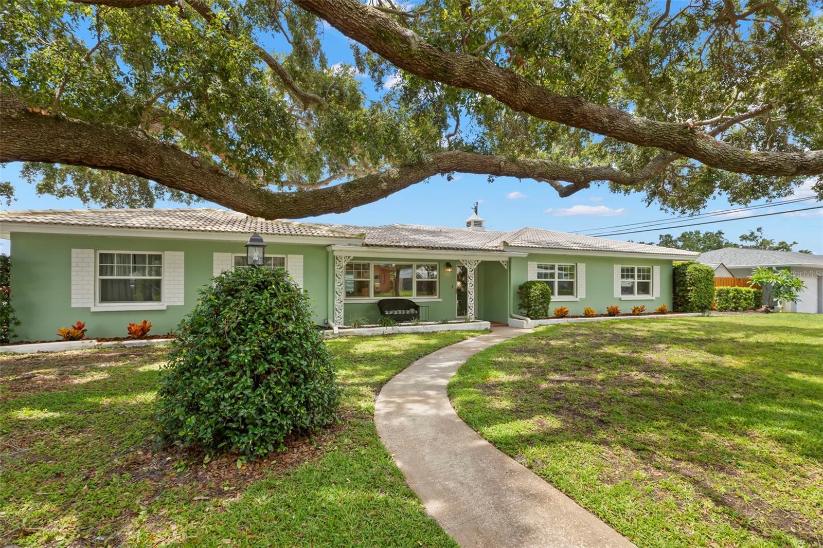 This beautiful 3 bed, 2 bath home is on the market for only the second time since it was built in 1957! It has been updated and lovingly cared for over the years and is ready for you to move in. The solar panels (2020) are PAID IN FULL resulting in an electric bill of approximately $35 for most of the year. Over the years, impact windows have been installed throughout, with the Florida room windows having just been replaced in April 2025. Inside you will find newer luxury vinyl plank flooring throughout the main living spaces. The kitchen has been remodeled with updates to the cabinetry, quartz countertops, new backsplash, and new oven, cooktop, and hood vent. Don’t like the kitchen cabinet color or wallpaper? The solid wood cabinets can be easily painted and the peel and stick wallpaper can be easily removed. The guest bathroom has also been remodeled with new marble flooring, new shower, vanity, and shiplap walls (2023). The home is also set up with a full home water treatment system. This location is high and dry and has NOT had any flooding issues. Situated on a corner lot, there is plenty of space to garden and play. The stunning oak tree is strong, sturdy, and provides an abundance of shade. The tile roof (recently pressure washed) is also strong and has lots of life in it (inspector said 11 years). The backyard has a brand-new paver patio and new sod (2025). It is a relaxing place to unwind at the end of the day. A new vinyl fence was installed in 2021. The home also has two sheds that are equipped with electricity. One is a she shed/office with air conditioning (2024) and the other is a storage/utility shed (2018). Other updates include a newer water heater (2023) and a new well pump and sprinkler system improved (2025). This home is full of character and charm and it can be yours!