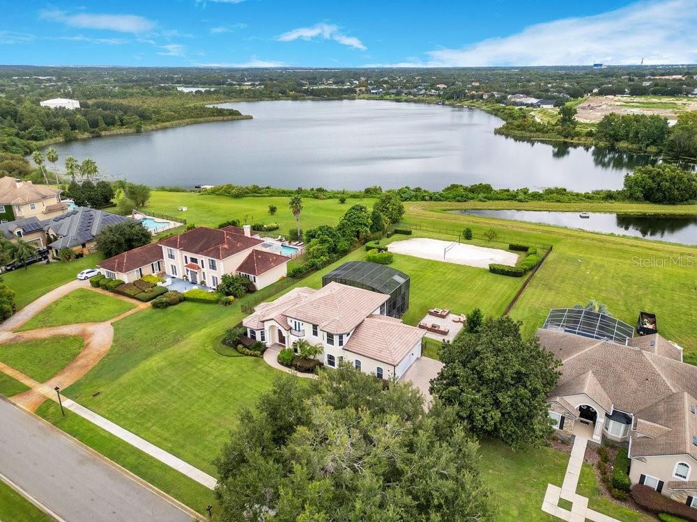 You have a great opportunity to own this custom 5-bedroom home with a heated saltwater pool, private volleyball court, 3 car garage, on a 1-acre lot with lake views, in a gated Windermere neighborhood with one of the best public-school ratings from kindergarten to 12th grade. This home has an amazing curb appeal with its timeless Mediterranean architecture surrounded with lush, manicured landscaping. The floor plan offers today's living with high ceilings, travertine floors, an elegant dining room with rich wood flooring, and 8’ doors throughout. The kitchen is fully equipped with a cooktop, center island, GE stainless steel refrigerator, kitchen exhaust fan, wood cabinets, granite counter tops, and plenty of storage space. The family room with a cozy gas fireplace is just off the kitchen and offers easy access to the pool area. The spacious main level primary bedroom suite boasts newer flooring, large walk-in closet, spa like bathroom with dual vanities, stone shower, and a jetted tub in the center. There are a guest bedroom and separate study conveniently located on the main level. Secondary bedrooms are all spacious with their own closets and bathrooms. This home offers so much space for entertaining especially with your own loft that be used for just about anything including a gym/flex space/movie room. There is also a veranda off the loft with breathtaking unobstructed water views. You will feel like you are on vacation when stepping out through the French doors leading to your screened in heated pool and spa overlooking Lake Cawood. The screened in lanai was designed for entertaining, relaxing in your pool, and hosting memorable barbeques from your summer kitchen. There is also an additional bathroom conveniently accessed from the pool area. You also have a large firepit patio with pavers to accommodate large parties and get togethers with loved ones. Give them a show like “Top Gun” from your very own white sandy beach volleyball court. Your home was built by award winning builder Sorenson Construction and features custom finishes throughout. Additionally, Lake Cawood Estates is a 24-hour gated community, with easy access to the major roads and highways, close to Orlando’s best attractions, shopping, and “A” schools. Sellers have spent over $130,000 on upgrades and have meticulously maintained the home. Notable upgrades include newer exterior paint, flooring, R.O. system, Remi Halo in-duct whole home air purifiers, Tesla car charger, and more. Don’t miss out on this extraordinary property! Be sure to click on the virtual tour links.