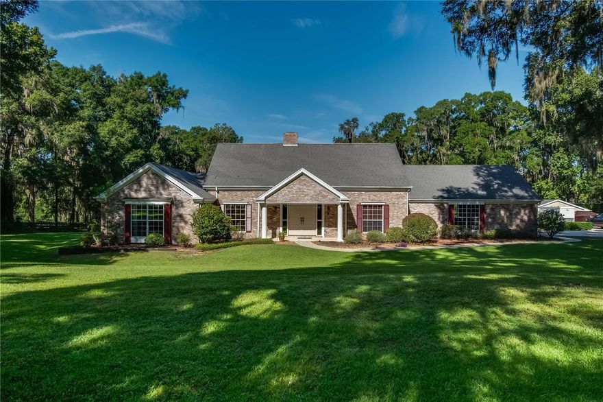 Nestled on a quiet stretch within the neighborhood of Shady Road Ranches, this stunning estate offers the perfect combination of private, picturesque, and convenient! Fenced and gated, the property has a picturesque setting and lots of curb appeal with just under 5-acres of gently shaded countryside adorned with professional landscaping. At the heart of the estate is the stunning 3-bedroom, 3-bath multi-story home. The first floor features the main spaces of the home, offering high ceilings, lots of natural light, and a spacious layout. A cozy fireplace serves as the focal point in the primary living area, making it the perfect place to relax on cooler winter nights. For those who enjoy cooking, the kitchen is well appointed– there is abundant cabinet and counter space, stainless steel appliances, tiled backsplash, under-cabinet lighting, and a large center island. Another unique feature in the kitchen is the pass-through window that directly connects to the Sun Room– a wonderful option that makes hosting a true breeze. The formal dining area is directly  connected to the living area and features lovely built-in shelving units with plenty of space for displaying collectibles, books, photos, and everything in between. The master suite is also located on the first floor, offering a stunning retreat that features a huge layout that includes a hallway with built-in shelving units, a private seating area with fireplace, a huge walk-in closet with shelving, and private en-suite with linen closet, large vanity, a large tub, and glass-door shower. If hosting is a passion, the back of the home is a perfect oasis to take advantage of. Outfitted with huge windows and ample space, the Sun Room is air conditioned and provides a built-in wet bar, entertainment area with TV, lots of space for seating, and ceiling fans to keep things cool. A pair of french doors open up to the expansive pool deck which surrounds the sparkling in-ground pool with diving board, all overlooked by an upper balcony with an exterior spiral staircase. Beyond is a huge backyard that has been meticulously maintained and landscaped. On the second floor are the remaining bedrooms and a shared bathroom. Both bedrooms feature direct access to the expansive second floor balcony, which directly overlooks the backyard and pool area, as well as attic access. Beyond the main home is a private studio-style apartment, which could be used for guest accommodations, in-laws, or even as a separate entertaining space or office if desired. Fully equipped with its own kitchen, a full bath, and ample space, there is tons of flexibility to how this space could be used! This property is located just minutes from the Florida Horse Park and a short drive from Ocala’s variety of shopping, dining, entertainment, and medical options, giving it the perfect blend of quiet and convenient! A must-see property that shouldn’t be overlooked, this charming estate is a true Ocala gem!