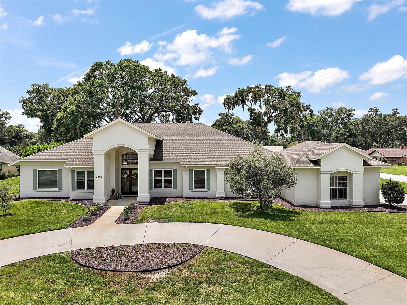 GORGEOUS 5 BR UPDATED POOL HOME ON A .52 ACRE FENCED PARCEL IN THE SOUGHT-AFTER LAUREL OAK COMMUNITY. This desirable, well-established community rarely has houses come up for sale. Today is your lucky day! This showstopper 3,700 SF home will dazzle you! Arrive home to this private sanctuary nestled onto a lush carpet of grass. The oversized .52 acre corner lot allows for a side-entry 3-car garage with an expansive driveway ensuring abundant parking for all. Around the front is a convenient circular driveway and a striking façade that commands attention. The paved walkway guides you to the covered portico, and the beautiful wood and glass double front doors beckon you inside. Prepare to be wowed as you enter to find a posh, stylish interior with 10-15 ft ceilings, glorious natural light streaming in from large windows (many recently updated), crown molding, rich wood flooring, stunning pool views, and an open, yet thoughtfully creative floor plan. The foyer is flanked by a formal dining room with a double-tray ceiling and a private home office/den (currently used as a bedroom). This front office features detailed millwork, custom-built-ins, and connects directly to the en-suite bath of the primary owner’s suite. Adjacent to the office and dining area is the living room, featuring a huge transom window and a triple slider glass door that opens to the pool and lanai. Through the living room, you'll find the open-concept kitchen, dinette, and family room. Wow, this space is fantastic! The kitchen exudes elegance with an abundance of finely crafted cabinetry, exquisite granite countertops, a custom herringbone backsplash, island with prep sink, built-in desk, upgraded stainless appliances, a stainless farmhouse sink, closet pantry, breakfast bar, and charming pool view dinette with built-in seating. The connecting family room offers a unique, custom-built-in for entertaining, offering stylish storage, an extra refrigerator, a wine fridge, and a bar sink. This space gets even cozier with a beautiful wood-burning fireplace. The extremely private primary suite is a luxurious retreat with abundant room for oversized furniture or a sitting area. Two custom walk-in closets hold all your treasures, and the spa-worthy en-suite features a dual Corian vanity, a custom-built-in for storage and display, a seamless glass shower with a rainfall shower head, and a free-standing deep soaking tub for the ultimate in relaxation. The front hallway features two bedrooms, an updated bathroom, a fully equipped laundry room, and a bonus utility room with built-ins, a utility sink, and space for an additional refrigerator. There’s a guest powder room, and off the family room is a second home office with double doors and access to the full hallway bathroom and bedroom 4. Bedroom 5 enjoys pool access and a private bathroom. Close the pocket door in the family room and create a private retreat in the rear of the house for extended-stay guests or as an in-law suite. The fabulous pool lanai is accessed from multiple rooms and offers a screened enclosure with covered areas for lounging and dining. There’s even a decorative electric fireplace and a summer kitchen with grill, bar, sink, and prep area. Privacy abounds with a fully fenced backyard. Imagine the parties and family fun you will have here. Located just minutes from The Villages, this home combines luxury, functionality, and a prime location for dining, shopping, and entertainment. Welcome home!