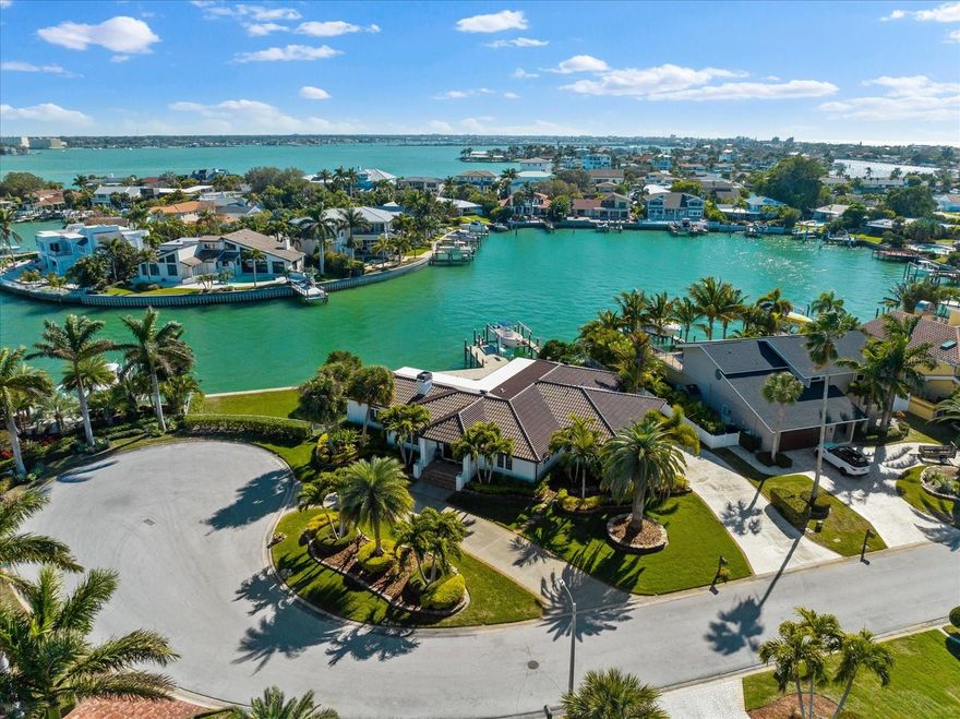 Imagine waking up to dolphins playing your back yard – an everyday paradise awaits you, come experience waterfront living at its finest in this exceptional property where every detail has been carefully curated to exceed your expectations. This renovated meticulously crafted residence boasts unparalleled features and thoughtful design elements throughout. Situated on a rare expansive lot on this highly sought after street and perfectly positioned on the quiet cul-de-sac, this property offers 157 feet of pristine deep waterfront, ensuring breathtaking views from every angle. Upon arrival you will notice the wonderful landscaping and tropical variety of palms with a gorgeous circular drive and plenty of parking for guests. Once you step through the double door entry into the foyer a feeling of comfortable elegance begins, seamlessly blending open living space with timeless sophistication. The heart of the home lies in the meticulously planned, one-of-a-kind kitchen for the chef in your family, also featuring hidden storage and charging station. Gather with loved ones in this amazing open concept floor plan design, enhanced by a wood-burning fireplace for cozy evenings in. Retreat to the tranquility of the split bedroom plan, offering four bedrooms plus a versatile home office or gym space. Step outside to discover a private saltwater pool with a sun-shelf, pavered patio deck, perfect for parties, heightened seawall and a custom composite dock equipped with a fish cleaning station boasting a 16,000 lb boat lift. Indulging in a day on the water has never been easier, as the deep water lot is never tidal dependent. Quick access to Clearwater Pass to enjoy the wide-open waters of the Gulf or waterfront restaurants with boating access.  Ample side yard space and a lush grassy area provide the perfect backdrop for outdoor activities and entertaining, and a large yard for Fido to run around. Enjoy resident only private Gulf front parking for a stroll on the beach or jaw dropping sunsets. Belleair Beach living is second to none. Schedule your private tour today and elevate your lifestyle to new heights.