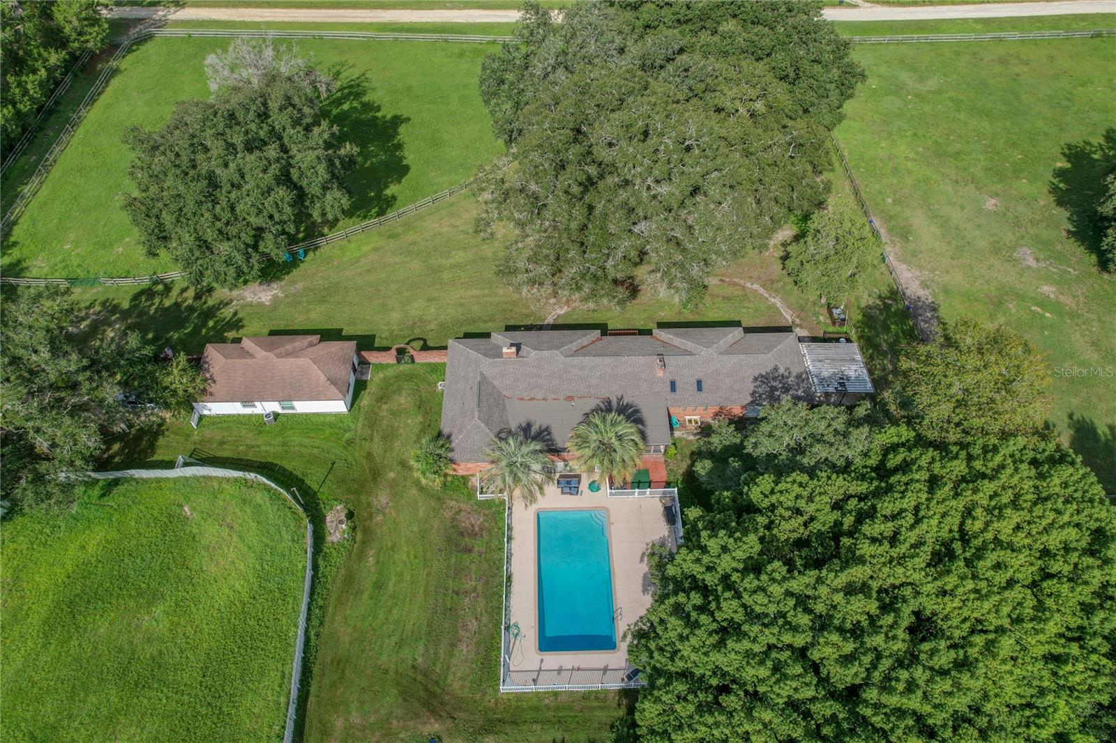 Absolutely stunning Farm close to World Equestrian Center! Drive up to a beautiful view of luscious green acreage. The main house has 4 bedrooms and 4 bathrooms. Walk into an expansive open floor layout. This luxurious kitchen has granite counters tops, a tremendous amount of cabinets and counterspace, bar seating, all stainless appliances and everything you need to cook up a top notch meal. Separate dining area with seating for six. Living room has nice custom fireplace and comfy couches. First guest bedroom has a Queen size bed and private bath. Second guest room has bath just outside and double size mattress bunk bed w twin trundle and twin day bed. Third guest room has queen size bed and private bath. Master bedroom suite has a king size bed, fireplace, TV and a desk with workspace. Master has a walk-in closet. Master bathroom has a huge Roman Tub for two as well as a separate shower and double vanity. Master has private access to lanai to sit and enjoy your morning coffee and view of the horses. There is also a separate lanai area from the kitchen. Large two car garage has space for 1car and a living area but could easily be converted back to two car. Enjoy nights by the firepit with friends, barbeques out back or just take a nice dip in the pool after a long day of horse training. The guest house has two bedrooms with queen beds, one full bathroom, a separate eat in kitchen area and a living room for lounging. The property has 5 fenced in paddocks and a barn with 4 stalls with a large tack room. Beautiful oaks trees and lush green fields. This place is perfect for your retreat! Minutes from WEC, shopping and medical.