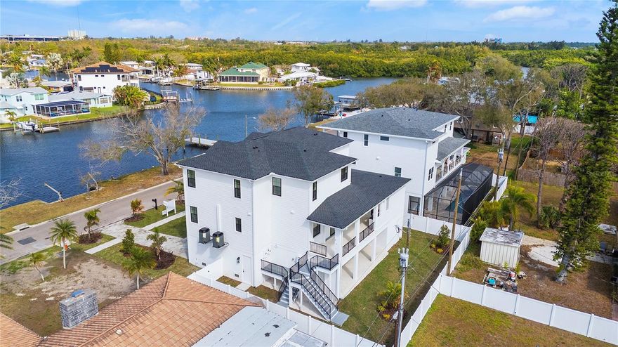 WATERFRONT NEW CONSTRUCTION — NOW COMPLETE & MOVE-IN READY! Located in the sought-after Riviera Bay neighborhood of St. Petersburg, this exceptional 4-bedroom, 4-bath residence offers 3,673 square feet of thoughtfully designed living space along with 54 feet of deeded waterfront frontage directly across the street. The property’s waterfront parcel features a seawall and offers the potential to construct a private dock or lift, providing convenient boating access to Weedon Island and Tampa Bay. The elevated three-story design provides peace of mind along with sweeping water views. A grand front staircase, welcoming covered porch, and private owner’s balcony create striking curb appeal and timeless coastal architecture. Inside, the foyer opens to formal living and dining spaces before flowing into the heart of the home. The chef’s kitchen features an oversized island, quartz countertops, designer cabinetry, a butler’s pantry, and a walk-in pantry—seamlessly connecting to the spacious family room and covered lanai for effortless indoor-outdoor living. A main-level guest suite or office offers comfort and privacy, while the first-floor pool bath provides convenient access from both the hallway and patio—ideal after a day on the water. Upstairs, the primary suite serves as a private retreat with its own balcony overlooking the water, a spa-inspired bath, and a generous walk-in closet. Two additional bedrooms share a Jack-and-Jill bath, and the upstairs laundry room adds everyday convenience. A pre-wired elevator shaft has been incorporated for future flexibility. Outdoor living is central to the design, with a covered lanai, summer kitchen, full pool bath, and space ready for a custom pool. At ground level, the expansive three-car garage provides abundant storage for kayaks, paddleboards, a golf cart, and more. Finishes were carefully curated by the design team and include wide-plank hardwood flooring, quartz countertops, statement lighting, and premium fixtures throughout. The home is also pre-wired for a fully integrated smart-home system, including hardwired security, surround sound, multiple audio zones, Cat6 wiring, and whole-home Wi-Fi—ideal for modern living, entertaining, and remote work. A rare opportunity to own new construction with deeded waterfront frontage and boating potential in one of St. Petersburg’s most desirable waterfront communities.