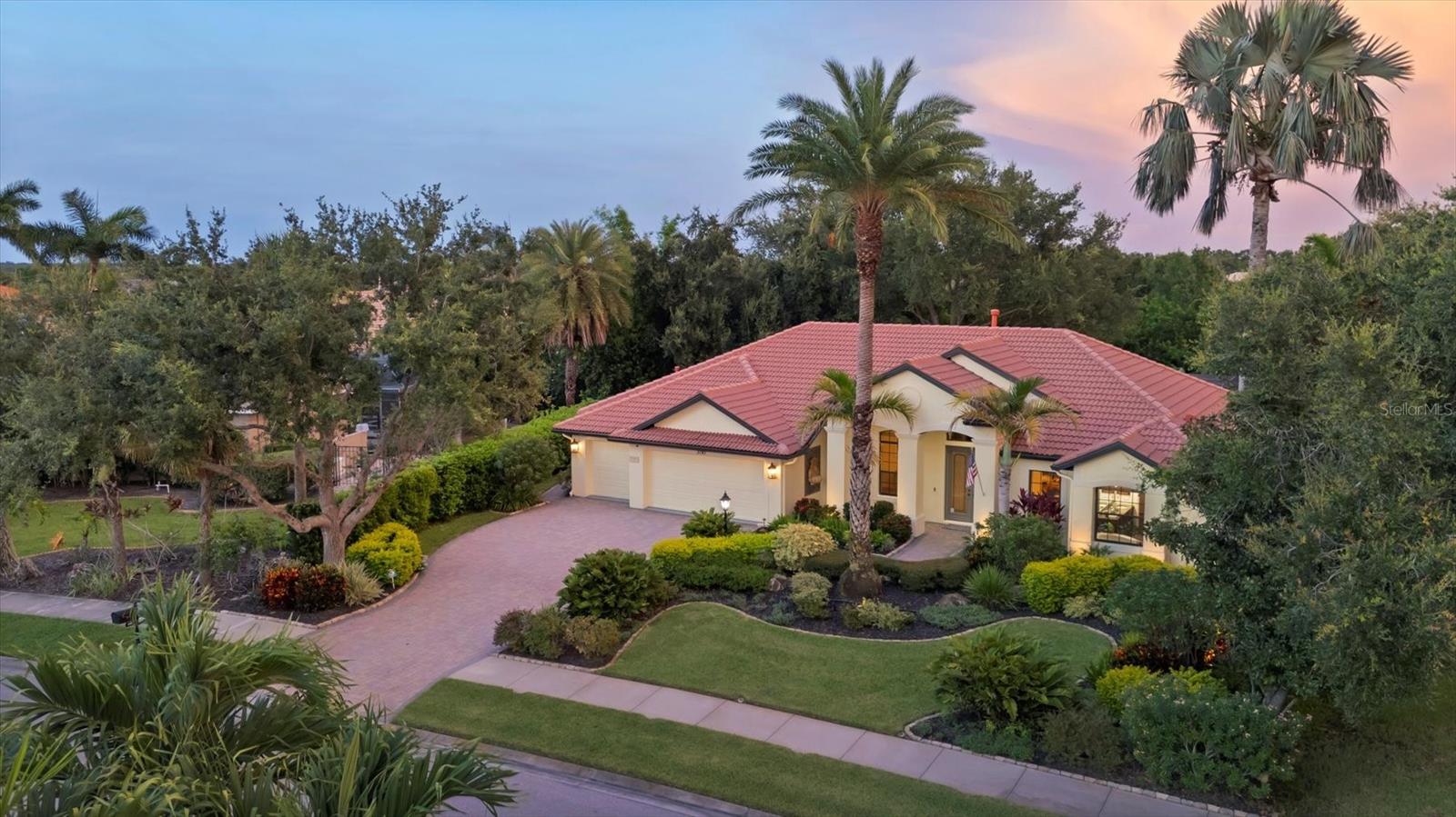Presenting a meticulously maintained custom-built pool residence by Coachman Homes, situated within the impressive gated community of The Hammocks in Sarasota. Constructed in 2006, this expansive home offers four bedrooms, three bathrooms, a dedicated den/office, and a three-car garage, all positioned on a premium preserve-view lot surrounded by mature, lush landscaping. Upon entry, one is immediately welcomed into the spacious foyer and the formal living room, which seamlessly flows to an extensive lanai featuring a heated pool and spa, complemented by tranquil preserve views. The interior showcases ceramic tile flooring throughout and impressive ceiling heights ranging from 14 to 20 feet, with elegant tray and double tray ceilings accentuating select main rooms. A notable enhancement to this property is comprehensive hurricane protection for all openings and a whole-house gas generator installed in 2019, ensuring peace of mind. The chef’s kitchen is appointed with a five-burner gas cooktop (with updated vent), double ovens, a large modernized center island, slide out shelves in the cabinets and open sightlines to both the family room and lanai—ideal for entertaining. The space is further enriched by a double-sided gas fireplace serving both the kitchen and living room. An exceptional feature is the fully enclosed, climate-controlled second kitchen/outdoor kitchen, outfitted with a mini split A/C, three-burner gas grill, side burner, commercial vent hood, refrigerator, dishwasher, wine cooler, beverage cooler, and direct access to the lanai and pool area with scenic backyard views. The primary suite boasts double entry doors, private pool access, picturesque views, separate walk-in closets (with upgraded closet system), tray ceilings with crown molding, a jacuzzi soaking tub, walk-in shower, and dual sinks. The office/study is enhanced by custom built-in cabinetry and high-quality wood flooring. Recent updates include a new refrigerator (2018), dishwasher (2025), washer & dryer (2021), AC units (2021 & 2016), wine and beverage refrigerators (2021), pool pump (2020), pool heater (2023), and a new water heater. The irrigations system, sourced from a private well, supports the vibrant landscaping, and landscape lighting elevates the property’s curb appeal. This distinguished home blends elegance, comfort, and fine craftsmanship within one of Sarasota’s most sought-after communities.