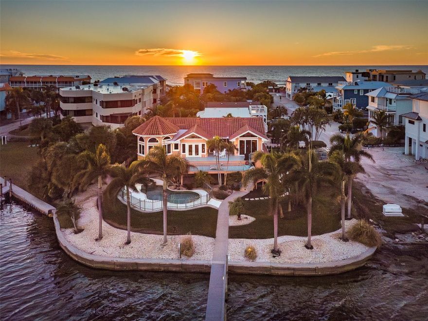 Relish a fabulous indoor-outdoor island lifestyle with breathtaking water views in this beautiful residence on Sarasota Bay. Situated on an oversized double lot at the end of a street, the Bradenton Beach home is surrounded by towering palms and lush landscaping, with spectacular east-facing water and sunrise views from the kitchen, living room, office, and primary bedroom. Less than 450 feet away is a serene beach on the Gulf of Mexico for enjoying seaside strolls and stunning sunsets. Bay views are visible from the moment you enter the inviting foyer with terra-cotta floors, which opens to a living room with pecky cypress wood walls and ceilings, and wood floors. Sliding glass doors transition to an expansive multi-level deck for relaxing, dining, and savoring bay, pool, and spa views. Chefs and guests will be right at home in the spacious well-appointed eat-in kitchen, featuring wood floors, solid wood cabinets, Corian countertops, tile backsplash, stainless-steel appliances, and gorgeous bay views through large sliders to the deck. The octagon-shaped primary bedroom boasts views of Sarasota Bay from every window, a 17.5-ft ceiling and an en-suite bathroom with a sizable walk-in shower and large walk-in closet with built-ins. A light-filled office offers French doors to the deck. On the ground level, the pool and spa are perfectly positioned along the bay, with an approximately 120-foot concrete seawall. Boaters will delight in the 6’x19’ dock with composite decking, three-point moorage, electricity, fresh water, and 13,000 lb. lift. The water depth at the lift and dock is at least 4' in most tide conditions, with a legally dredged channel at the dock for access to the Intracoastal Waterway—no fixed bridges. Additional space is available on the ground-level, which is fully enclosed and has three storage rooms, two flex spaces and exterior entrances. The ground-level also has a multi-use covered patio. Other notable highlights include an interior elevator, oversized garage, and single-vehicle carport with garage door. The last remaining single-family primary residence on the street, it is in the 1–7-day rental zone, making it an attractive investment opportunity. There is incredible potential to divide the double lots and build two separate income-generating vacation rentals. Additionally, with some updates, the home could be used as a vacation rental.