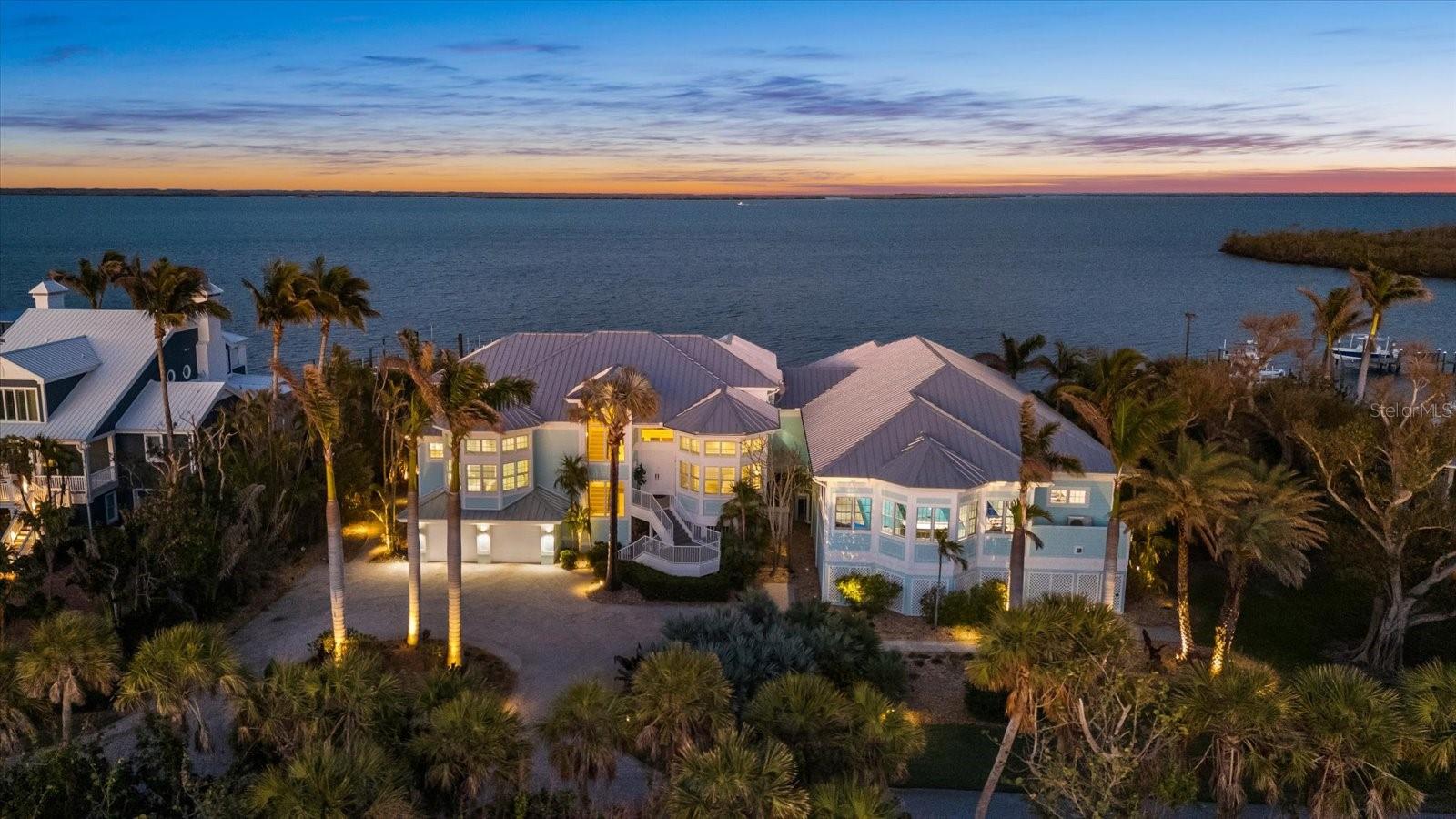 2 DEEP-WATER DOCKS AND A COVERED 10,000 LB LIFT. 5 BEDROOMS AND 5.5 BATHROOMS. MYRTHA POOL. INDOOR GUN RANGE. NO FIXED BRIDGES TO GULF WATERS. Welcome to a true Sportsman’s Paradise at 14 Grouper Hole Drive on Gasparilla Island in Boca Grande, Florida. This exceptional waterfront estate offers an unparalleled lifestyle, where breathtaking views of the Gasparilla Sound greet you the moment you step through the grand double doors. Designed for both adventure and relaxation, this residence seamlessly blends refined elegance with world-class amenities. The main living area is on the second floor, accessible by a three-stop elevator. A bright foyer leads into the expansive living room, which is open to the third floor, creating an impressive sense of space with soaring ceilings. The dining area flows effortlessly into the kitchen, where a beautiful bay window breakfast nook offers the perfect setting to enjoy morning coffee with stunning water views. The kitchen features a WOLF gas stove, a Sub-Zero paneled refrigerator, a spacious pantry, and a breakfast bar. French doors from the living room open onto a large screened deck—ideal for entertaining or unwinding as boats pass by. The second floor hosts three guest bedrooms, each with nearly floor-to-ceiling windows and en-suite bathrooms. A half bath and a well-appointed laundry room are also on this level. A striking catwalk on the third floor, adorned with a sculptural iron railing, overlooks the living space below while offering sweeping views of the Sound. The luxurious primary suite is a serene retreat, with private access to an open-air deck to enjoy the waterfront breeze. The en-suite bath features dual vanities, a walk-in shower, and a separate soaking tub. A generous walk-in closet with custom shelving provides ample storage. An additional sitting area with a bay window offers yet another breathtaking vantage point. A well-appointed fifth bedroom, also with mesmerizing water views and an en-suite bath, is located opposite the primary suite. The estate’s crown jewel is the extraordinary sports pavilion, seamlessly connected to the main home. Designed for ultimate recreation, it features an indoor/outdoor sitting and dining area with a retractable mosquito screen and fire pit. Inside, a stylish living space and fully equipped kitchen boast Viking appliances, Kendall Cambria Quartz countertops, a built-in bar refrigerator, and an ice machine. At its heart is the Myrtha Ozone Pool—one of Florida’s most advanced residential pools. Competition-length, with stainless steel bolted technology for durability, it features a European lighting system, the only one of its kind in North America. Exceptionally pure, the water is free of chlorine and salt, making it pristine enough to drink. The pool is both heated and cooled for year-round enjoyment, with a standalone hot tub nearby. The sports pavilion also includes a private, air-conditioned Pilates studio and areas for ping pong and billiards. For shooting enthusiasts, the state-of-the-art gun range features two dedicated lanes—one for archery and one for firearms. Equipped with a high-tech camera system for precision accuracy, a retractable target retrievals, advanced bullet entrapment, and sound suppression, this range ensures top-tier performance. Please copy and paste for a luxury tour: https://iframe.videodelivery.net/364fcc9f0e2e63c16df65d4a8f1f245e