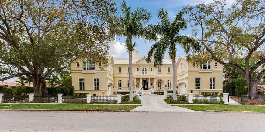 Experience the height of Livable Luxury in this extraordinary estate designed by Thomas Everett Lamb and built by Windstar Homes, an award-winning custom builder with over 100 industry accolades for craftsmanship and architectural excellence. Positioned on the open bay along Davis Islands, this one-of-a-kind residence blends timeless design with resort-style living. Created for grand-scale entertaining and refined everyday living, the home captures sweeping bay views, expansive terraces, and meticulously curated interiors. A stately arrival welcomes with parking for 9 vehicles and a 4-car garage, framed by hand-cast cement trim, shell detailing, and custom copper lanterns. Twin fountains accent the circular glass-paneled French doors, opening to a breathtaking foyer highlighted by a sweeping spiral staircase, intricate filigree ironwork, layered crown and dentil moldings, and a dramatic domed ceiling. The Grand Salon and formal dining spaces, including a dining alcove flanked by dual wine rooms with beveled glass, feature hardwood floors, hand-carved limestone fireplaces, and floor-to-ceiling arched windows. Walls of glass frame the west-facing veranda, gazebo, pool, fire pit, party dock, pickleball court, and unobstructed open bay. Exceptional craftsmanship is evident throughout, with concealed air-conditioning vents seamlessly integrated within the crown molding, deep windowsills, and extensive custom millwork. The chef’s kitchen centers around a massive island with beveled stone countertops and dual crystal chandeliers, complemented by Sub-Zero refrigeration, double dishwashers, and a Wolf range with griddle. A fully equipped scullery kitchen offers commercial refrigeration, double ovens, and additional prep space, ideal for catered events. A butler’s pantry, mudroom, and secondary laundry enhance daily functionality. Seamless indoor-outdoor living unfolds as the kitchen and great room open to a covered terrace featuring a pizza oven, warming drawer, beverage refrigerator, ice maker, sink, gas grill, and generous seating and dining areas overlooking the pool and bay. The first level also includes a bayfront office with custom cabinetry and fireplace, a game room with bar and adjacent theater, as well as a gym, craft, and multipurpose spaces. A private guest suite with rotunda seating, kitchenette, and elaborate bath completes the main floor. Upstairs, the primary suite is a private sanctuary occupying nearly one-third of the level. Entered through a grand vestibule, it features a bayfront sitting room with terrace access, limestone fireplace, dual custom walk-in closets with crystal chandeliers, and a spa-inspired bath with fireplace, steam shower, and marble finishes. Additional bedroom suites offer ensuite baths, custom cabinetry, and tranquil water or garden views, with many opening to private terraces. A separate guest or nanny suite, accessible via stairs and a hidden passage, includes a full kitchen, living area, bedroom, walk-in closet, laundry, and full bath. Outdoor living rivals a private resort, with a gazebo featuring marble bar seating for ten, a resort-style pool, fire pit, multiple terraces, pool baths, and a fully equipped kitchen. A crow’s nest terrace captures west-facing sunsets over the bay. With elevator access, 3 staircases, integrated technology, whole-home audio, and thoughtfully designed flow, this Davis Islands estate delivers architectural grandeur, modern luxury, and an unparalleled waterfront lifestyle.
