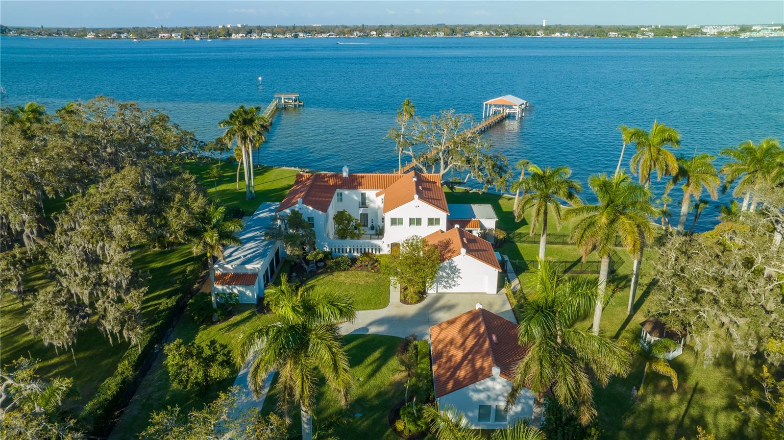 Auction Property. AUCTION BIDDING OPEN: Bidding ends December 14th. Previously Listed $4.95M. Current High Bid $3M. No Reserve. Saturday and Sunday 1-4pm, and Showings Daily By Appt.
This gorgeous, Spanish-style estate sits on almost two acres with panoramic views of the Manatee River from nearly every room. Old-world charm meets modern luxury in this waterfront piece of paradise. The compound features a beautiful main house with abundant natural light and room for entertaining, from the comfortable living areas to the spacious kitchen with waterfall countertops and stainless steel appliances. The primary suite has a stunning bathroom with a freestanding tub and a sun-drenched dressing room. The estate also features a beautiful wood-paneled office, a studio space, and a first-floor bedroom with an ensuite bathroom and separate entrance. Take a dip in the heated indoor/outdoor pool or enjoy a tropical cocktail on the screened lanai overlooking the water. The brand-new dock and boat house features power lifts for Jet Ski’s and a 16,000-pound boat lift so you can enjoy watersports in your backyard. This tropical gem includes a .31 acre lot at 2832 Riverview Blvd, where you can build an additional house for relatives or guests.