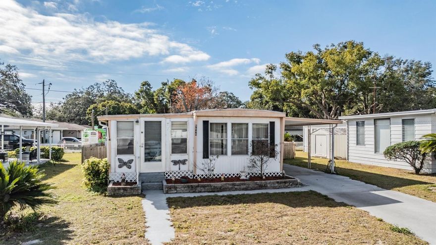 Title in place / Own the land! This 1970 2/1 mobile home has Hurricane straps, a security system along with a long driveway and carport area for tandem parking. NO FLOOD - LOW TAXES - OPTIONAL HOA ($35.00 A YEAR).  April 2024 all new planks, plywood and bracing were installed (value: $12,000) in the kitchen, hallway, bedroom 2 area. Gutters and downspouts are attached. This dwelling boasts of large rooms and a  fenced backyard next to an alleyway. Enter into a 27 x 10 family room with 3 large windows and a wall to hold an enormous television.  The kitchen is shared with the dining area in the front of the dwelling allowing the view of the front yard. An exterior raised flower bed box is next to the front entrance.  A double sink is under a pass through window into the family room.  Roof membrane is in good shape.  HVAC (3.0 ton) and thermostat are 2 years old with all new duct work just installed under the trailer.  The electrical panel was upgraded in 1991. A spacious  walk-in closet in the first bedroom includes an extended area great for another bed, office, sitting area, etc. A large shower bathroom will not disappoint with a new toilet.  Down the hall is a second bedroom with a regular closet and a complete wall unit bearing 5 doors and 6 drawers. Plenty of storage for any clothes.  There is a storage shed bearing a washer/dryer hookup and electricity just out the back door.  The hot water tank is housed within a storage shed within the fenced yard.  The second storage shed also has electricity and lots of shelves.  A new plumbing drain pipe to the septic tank was professionally installed. Enjoy the optional clubhouse ($35.00 annually) for coffee or having a party. Take advantage of nearby shopping & restaurants. The Gulf of America, MacDill Air Force Base, hospitals, the new VA Outpatient hospital, the forthcoming H. Lee Moffitt Cancer Center and Research Institute (with a world-class expansion campus in Pasco County within a few years), beaches, and numerous other attractions are convenient. Tampa and St. Pete Clearwater Airports are appx 30 minutes away, granting easy access to anywhere in central Florida. Your playground awaits!