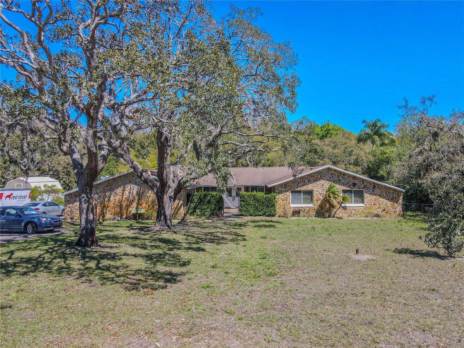 Tucked away on 1.27 shaded and fenced acres, this 4-Bedroom, 3-bath Pool home feels like your own private hideaway while still being just minutes from shopping, dining, and medical services. And there are no HOA or deed restrictions to worry about.
As you pull up the long driveway, you’ll notice there’s more than enough space for RV or boat parking. At the end, you’ll find a detached two-car garage complete with a workbench, perfect for weekend projects or extra storage.
Step through the double-door front entry, framed by stone accent walls and steps, and you’re welcomed into a foyer with beautiful beveled glass doors, tile floors, and a decorative wrought iron archway. Just past that, you step down into a massive living and dining room combo, where ceiling fans and tile floors keep things comfortable and breezy.
The heart of the home—the kitchen and family room—features vaulted ceilings with exposed wood beams that give the space warmth and character. The kitchen is well-appointed with solid wood cabinets detailed with crown molding, granite countertops, and stainless-steel appliances, including a built-in convection oven and microwave, electric cooktop, and a French door refrigerator with ice and water dispenser. The space is complete with a stainless-steel sink with a pull-down sprayer and a breakfast bar with extra seating and a built-in wine rack.
The kitchen flows seamlessly into the family room, where more vaulted ceilings with wood beams, track lighting, and a ceiling fan create an open yet cozy space. A wood-burning fireplace with a stone facade and hearth adds charm and makes it perfect for gatherings.
Just off the family room is a spacious bonus room (26'.1" x 15'.7") with two sets of French doors that open to the screened lanai and pool area. The bonus room is a flexible space—you can tailor it to whatever you need, whether a home office, gym, media room, or playroom. The possibilities are endless.
The screened-in lanai provides for both sun and shade, with a covered patio cooled by ceiling fans and plenty of space to unwind poolside. The pool is large and private, framed by mature trees and fencing that give you a quiet place to relax or entertain.
The primary suite is calming with neutral tones, wood-look laminate floors, a ceiling fan, two walk-in closets, and an ensuite bath. The ensuite bath has a dual-sink wood vanity topped with granite, downlight fixtures, and a step-in shower. Plumbing is already in place if you’d like to add a tub. The primary bedroom has sliding doors to a private space on the lanai—ideal for morning coffee.
There are three additional bedrooms. Bedrooms 2 and 3 each feature tile flooring, ceiling fans, and built-in closets.
The 2nd bathroom features a mirrored wood vanity with storage and hanging pendant light, a ceiling fan with a light kit, a tile floor, and a tub with a shower.
On the opposite side of the home, the fourth bedroom offers even more privacy, along with a sitting area, built-in closets, and shelving. The beautifully updated third bathroom features a glass-enclosed shower, rain showerhead, deep soaking tub, and stone-topped mirrored vanity.
A dedicated laundry room includes a front-load washer and dryer, built-in cabinetry, and a sink to make chores a little easier.
Outside, the fenced backyard is shaded and private—ideal for pets, play, or simply enjoying the peace and quiet of your surroundings.