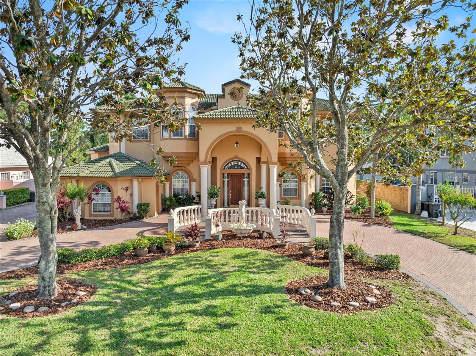 Discover an exceptional custom-designed residence in the highly desirable South Bay community of Southwest Orlando's Dr. Phillips area. This magnificent single-family home, crafted by a renowned architect, exudes sophistication from the moment you arrive via the improved brick paver circular driveway, framed by elegant columns and a distinguished Spanish tile roof. Step inside this impeccably maintained and move-in-ready home to experience a sense of refined living, greeted by a striking split staircase. The formal living spaces showcase soaring 16' pocket tray ceilings and designer chandeliers, setting a tone of understated elegance. 1 The state-of-the-art kitchen, recently modernized with refaced cabinetry and a full complement of high-end GE Cafe appliances, seamlessly flows into the expansive family room, perfect for both intimate gatherings and grand entertaining. Each of the five spacious bedroom suites offers a private sanctuary with walk-in closets and en-suite bathrooms. A substantial private office, featuring a 16' tray ceiling, provides an ideal workspace. Enjoy tranquil views of the custom pool, complete with a spa and fountain, from the private balcony. This home boasts superior construction, including block construction and steel-wrapped rafters for added security. The screened outdoor living space is an entertainer's dream, featuring the stunning pool and spa, a convenient pool house with a shower and grill, and a unique custom mural. South Bay offers residents exclusive amenities such as 33 acres of common grounds, 2.5 miles of walking paths, private tennis courts, and access to the Chain of Lakes. 2 Its premier location provides unparalleled convenience to Orlando's top attractions, including world-class dining on Restaurant Row, the renowned Bay Hill Golf Course, major theme parks, downtown Orlando, and the Orlando International Airport, with easy access to Florida's famed beaches. In the South Bay community, residents enjoy exclusive access to the renowned Butler Chain of Lakes via a private dock on Lake Tibet – perfect for fishing, recreation, and enjoying breathtaking sunsets. Families are drawn to this area for its exemplary Dr. Phillips schools. This remarkable property, enhanced by a new air conditioning system, presents a rare opportunity to own a distinguished home in one of Orlando's most sought-after neighborhoods.