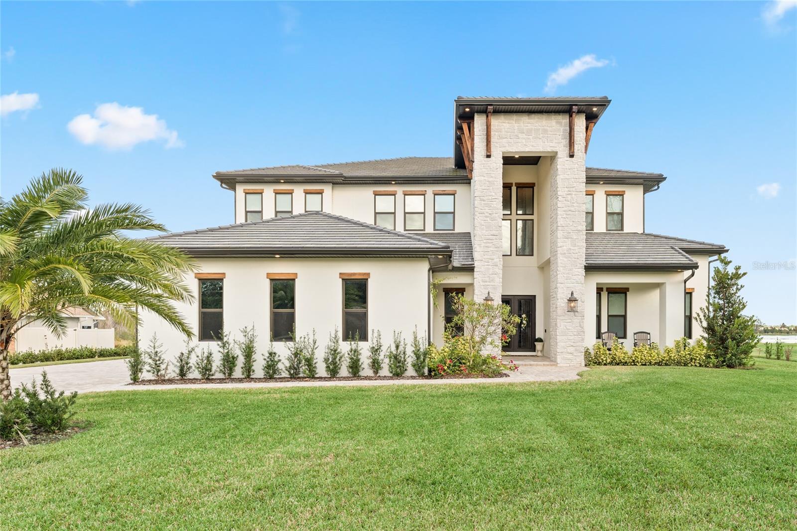 Step into a world of unparalleled luxury with this stunning estate on the shores of Lake Ajay in St. Cloud, Florida. Boasting million-dollar views and a lifestyle to match, this brand-new, 5,820-square-foot home is an oasis of sophistication, comfort, and convenience, just minutes from the world-renowned Lake Nona. This 6-bedroom, 5 full-bath, 2 half-bath home blends cutting-edge design with exceptional craftsmanship. Featuring expansive 12-foot ceilings downstairs and 10-foot ceilings upstairs, the open floor plan welcomes natural light into every corner. Hardwood floors flow throughout the living areas and bedrooms, while the bathrooms feature exquisite luxury tile finishes. The elevator offers seamless access to both levels, providing convenience and enhancing the home's luxurious living experience. Custom cabinetry graces every room, adding elegance and functionality. The chef’s kitchen is a culinary masterpiece, with quartz countertops throughout, a stunning backsplash, and custom kitchen cabinets that provide both beauty and functionality. Equipped with state-of-the-art appliances, including a custom refrigerator and a commercial-grade gas stove, this kitchen is designed to impress the most discerning chefs and entertainers alike. The master suite is a true retreat with breathtaking lake and pool views. Its spa-like en suite includes a stand-alone tub, a walk-in shower, and a massive walk-in closet that’s nothing short of a dream. Just steps away, a wine cellar adorned with white-washed brick creates the perfect setting for your finest collection. The theater room rivals any cinema with its plush seating and stylish décor. Guests will love the additional bedroom with an ensuite on the main floor and the loft and balcony upstairs, offering panoramic views of the sparkling lake and expansive pool area. Outside, the travertine-paved patio includes both an Olympic-sized pool and jacuzzi that provide the perfect backdrop for relaxation or entertainment, all set against the serene lake. This home sits on just under an acre and offers savings on both property taxes and community fees, making this a rare opportunity for high-end buyers seeking both luxury and value. The neighborhood itself is a haven of private amenities, including a private dock, private boat launch, and a full suite of tennis, basketball, and pickleball courts. Built in 2024 with top-of-the-line AC units, tankless water heaters, Appliances, Flooring, Cabinetry , Icynene insulation, and so much more! This home combines modern convenience with energy efficiency.Live the high-end lifestyle without the high-end price tag. Don’t miss out—schedule a tour today and experience everything this breathtaking home has to offer!