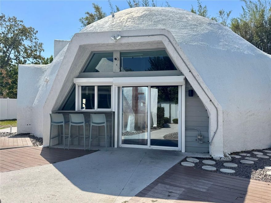 Discover a truly one-of-a-kind architectural residence nestled on nearly half an acre in the Broadwater community of St. Petersburg. This distinctive property features two geodesic dome structures, blending midcentury modern-inspired design with artistic elements and functional living. The main dome offers just over 1,400 square feet of living space, featuring 3 bedrooms and 2 bathrooms. The main living area showcases ceilings up to approximately 25 feet, creating an open, airy atmosphere with abundant natural light and striking geometric lines. At the heart of the home, a bold, design-forward kitchen complements the home’s midcentury modern aesthetic. Both stylish and functional, this space offers a blend of character and modern convenience suitable for everyday living and entertaining. The second dome is a versatile open-concept space with ceilings up to approximately 16 feet—well-suited for a guest space, creative workspace, private office, or other flexible uses. Combined, the property offers over 2,100 square feet of living space (buyer to verify). Each structure is positioned with its own private entrance, driveway, and yard space, offering flexibility and separation of use. This unique configuration may present opportunities for extended stays, guest accommodations, or other potential income-producing uses, subject to local zoning, permitting, and rental regulations. Designed with the Florida lifestyle in mind, the property features gated access points with room to accommodate boats, trailers, or recreational vehicles. The expansive lot provides additional outdoor space and storage options. Surrounded by mature landscaping and bamboo (native and non-invasive), the property offers a private setting while still part of the Broadwater neighborhood. Broadwater Park and nearby waterfront areas are located within close proximity. The property has been featured in national advertising campaigns. Originally designed with influence from a New York-based designer, the home reflects a blend of architectural creativity and design. This property presents a unique opportunity for buyers seeking a distinctive residence with flexible use potential. This is more than a home, it’s a rare opportunity to own a true work of art. Buyer to verify all measurements, uses, zoning, and any rental or income potential.