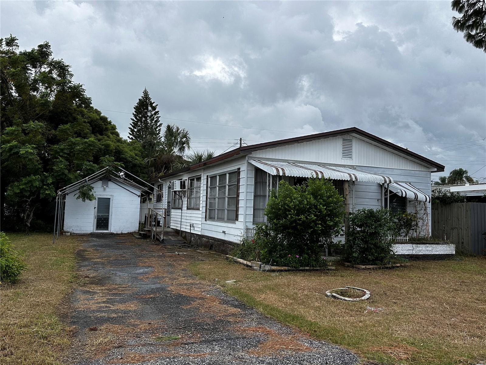 Own the land! Ideal location, with low HOA fees($109.50/quarter), no flood zone, no CDD fees, and low taxes. This charming 2 bedroom, 1.5 bath mobile home, designed to resemble a house with vinyl siding, partial gutters, a blacktop driveway and a frame to place a tarp, offers a multitude of benefits for any family. Upon entering, you are greeted by a spacious room with 2 sets of slider doors (could easily be converted into a third bedroom). The kitchen, located to the right, features wooden cabinets and a bar overlooking the dining room. Step down into the generously sized living room, complete with new wood-look flooring. A side door provides convenient access with a ramp and/or stairs for easy entrance. The two bedrooms at the back of the home are both generously sized, with the primary bedroom boasting an attached half bath. Second bedroom has cedar in the closet. The backyard is lush and green, enclosed by a privacy fence. Additionally, there are 2 large sheds under 1 roof which houses two washing machines, a dryer, and a shower. A separate back shed provides secure storage space. Enjoy shopping, restaurants, Gulf of Mexico, Suncoast Parkway, nearby MacDill AFB, hospitals, new VA Outpatient hospital, forthcoming H. Lee Moffitt Cancer Center and Research Institute will have a world-class expansion campus in Pasco County within a few years, beaches, and MORE at your fingertips! Tampa and St Pete Clearwater Airports are 30+ minutes away! Play anywhere in central Florida! Our playground awaits you !!