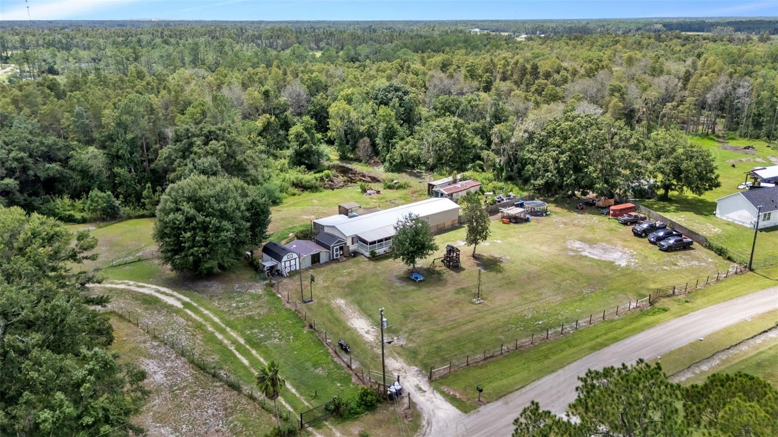 Experience the best of country living in North Lakeland with this spacious 2,400 sq ft, 5-bedroom, 3-bath manufactured home on 9.75 acres, just minutes from Hwy 98 N, and also near shopping, schools, and Colt Creek State Park. The property includes inviting front and back porches, an above-ground pool, a playset, goat and pig pens, and multiple sheds providing ample storage. Inside, the primary suite features a walk-in closet and an ensuite bathroom with a garden tub and walk-in shower. Ceiling fans and carpet are found in every bedroom providing additional comfort, and a separate laundry room adds convenience. The kitchen offers abundant cabinetry and modern stainless steel appliances, including a dishwasher and microwave. Recent updates include durable vinyl flooring in the main living areas and bathrooms. Blending modern upgrades with rustic charm, this home offers plenty of space for recreation, animals, and the true Florida country lifestyle.