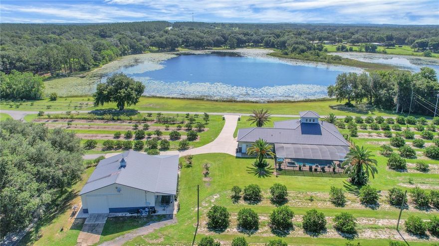 Step into luxury and tranquility with this stunning lakeview pool home nestled on 13.74 acres, built in 2015 and exterior freshly painted in 2024. The main house offers 3 spacious bedrooms and 2 bathrooms plus there is an additional 1 bed 1 bath guest quarters with kitchen plus living room! Southern Living at its finest when you are greeted by this expansive (55 x 14) Veranda with pavers overlooking your almost 100 feet of lake waterfront!  From the moment you enter, you’ll notice the rich hardwood floors flowing through the living and dining areas, complemented by crown molding and plantation shutters that add elegance throughout much of the home. The chef’s kitchen is a showstopper, featuring beautiful hickory cabinets, granite countertops, stainless steel appliances, a center island, breakfast bar, and a walk-in pantry—perfect for everyday living and entertaining. The primary suite is a serene retreat with double-door entry, diagonally laid tile flooring, and abundant natural light. The ensuite bath includes a double vanity with granite, a soaking tub, and a walk-in shower with a built-in seat. Enjoy convenience with an inside laundry room offering ample storage, counter space, and a utility sink. Step outside to your private oasis—a 7.6 foot deep saltwater pool with a hot tub, all surrounded by pavers that extend into a covered lanai. Surround sound is installed throughout most of the home and continues into the pool area for the perfect entertaining experience. A durable commercial-grade metal roof and gutters offer long-term peace of mind. Guests will love the separate, tiled guest house which includes a bedroom, bathroom with walk in shower, living room, kitchen and 54 X 13 covered porch—— ideal for extended stays or potential rental income. The Living Room Fireplace, the pool heater, the fire pit and the grill are all supported by a 250 gal GAS propane tank.  Attached is a spacious Morton Barn with an RV-height door 12’6 plus 2 electric 10 ft doors providing incredible storage or workshop potential. A peaceful koi pond adds to the serene atmosphere, making this property feel like a private retreat—yet it's just 15 minutes from shopping, restaurants, medical facilities, and The Villages.  Copy and Paste this link to view the video:  https://bbemaildelivery.com/bbext/?p=video_land&id=11FC600B-78C8-48E3-A16F-DF5D3DDDB169
