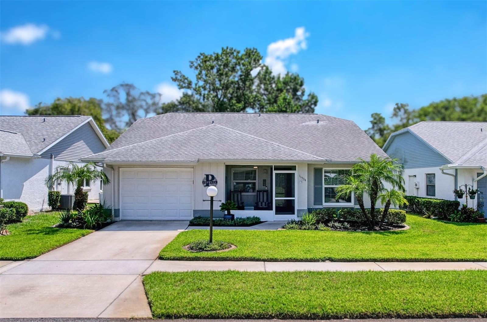 Welcome to this beautifully UPDATED, move-in ready home, thoughtfully appointed with HIGHER-END finishes that elevate comfort, style, and peace of mind. Located in Arborwood at Summertree, one of Pasco County’s most sought-after 55+ resort-style communities. This charming 2-bedroom, 2-bathroom residence is situated on a serene POND LOT, offering peaceful views and a sense of tranquility that perfectly complements an easy Florida lifestyle. As you approach, the inviting curb appeal shines through with refreshed landscaping, concrete curbing, gutters, NEWER hurricane-rated windows with divided light style, and an impact-rated garage door. Walk up to your cozy screened front porch with remote fan, wood-look tile flooring, and smart lock which leads to a show-stopping leaded glass front entry door welcoming you home. Inside, you’ll immediately notice the pride of ownership reflected in the warm, inviting finishes. LUXURY deep-tone vinyl plank flooring catches your eye and flows seamlessly throughout the living space. The Kitchen, redesigned in 2019, features designer wood soft-close cabinetry, corner carousel, roll-out shelving, modern STAINLESS STEEL appliances, closet pantry, under-mount sink with high-arc pull-down faucet, garbage disposal, coordinating backsplash, and leveled-up GRANITE countertops that truly sparkle. The kitchen connects effortlessly to the dining and living areas, creating a layout ideal for entertaining or quiet moments at home. The spacious open living area features vaulted ceilings, a remote-controlled ceiling fan, and overlooks the screened patio and peaceful pond. The split bedroom design offers privacy while maintaining a generous primary suite with pond view, walk-in closet, and an UPDATED en-suite bath with walk-in shower. The common bathroom has been fully renovated with a tiled walk-in shower, vanity, fixtures, and exhaust fan—delivering beauty and function. Step outside to your screened and covered patio, complete with aluminum roof (2023), a remote ceiling fan, and Blink camera. A perfect spot to unwind while enjoying views of cranes, ducks, and the occasional deer. Significant mechanical upgrades include a 2019 roof w/3rd nail support, 3-ton HVAC with Wi-Fi thermostat (2024), water heater (2025), upgraded electrical panel with labeled circuits and added outlets, whole-home water softener, updated smoke/carbon monoxide detectors, and a hardwired Ring doorbell for added security. The garage is fully outfitted with built-in cabinetry, a trendy pull-down workbench, shelving, utility sink, NEWER washer and dryer (2024), and a remote-entry keypad—blending smart enhancements with everyday comfort and making this home a standout in the community. Arborwood is golf-cart friendly and part of the vibrant Summertree neighborhood, celebrated for its active social calendar, golf course, and impressive amenities. The HOA fee includes lawn care, irrigation, trash, CABLE, and INTERNET for a low-maintenance lifestyle. Residents enjoy a well-appointed clubhouse, fitness center, pools, spa, tennis and pickleball courts, shuffleboard, billiards, and more. Whether you're looking for relaxation, recreation, or connection, this home offers the ideal balance. This exceptional property reflects thoughtful design, quality upgrades, and the type of care that makes it feel like HOME from the moment you arrive. Don’t miss this rare opportunity to live in comfort, style, and community—schedule your private showing today.
