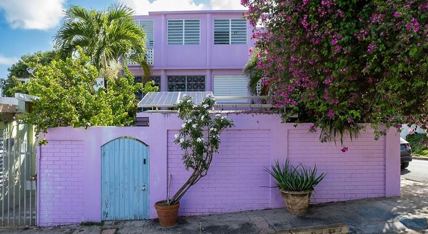 Casa El Palomar is a charming and welcoming home which has been family owned for decades.  The striking purple and sea blue building flanked by a massive and colorful bougainvillea has become a landmark in Isabel II, captured by countless photographers and painted by many local artists.  It is located on a quiet street at the heart of town and within a 6 minute walk to Sea-glass beach, and the hustle and bustle of some of Vieques’ best coffee shops, restaurants, and markets.
The core of the property is private courtyard similar to a Moroccan Riad.  The garden contains a collection of orchids and a wall-mounted seahorse sculpture created by locally renowned artist, Brooke Grant.  The encompassing tropical greenery provides a pleasant shade and privacy to the winsome jewel toned pool.
The architecture and decor is an eclectic mix of country chic meets the Caribbean with plenty of highly sought after outdoor living space.  On the lower level, a bright entry/receiving room connects with a marble and travertine tiled kitchen with garden side dining and a guest 1/2 bath.
On the second floor is the home’s main living room and adjoining screened in balcony with traditional decorative rejas that look over the courtyard.  The adjacent sitting room features a built in reading nook/day bed.  The quarters also have a private meditation/guest bedroom lined with ornamental breeze blocks and a full bathroom.
On the upper level master suite, the north facing bedroom and sun room have views to the ocean and has a large sun lit dressing room and full bathroom.  The south facing office/study and balcony have views of the fort.  Another guest room and balcony overlooks the charming street, where a spiral staircase can easily be added to have spectacular 360 degree views of the fort and ocean.
Meticulously maintained, AC throughout, a solar powered pool, 2 outdoor storage areas, and additional storage beneath the lower level stairs, this appealing home also provides convenience and comfort.